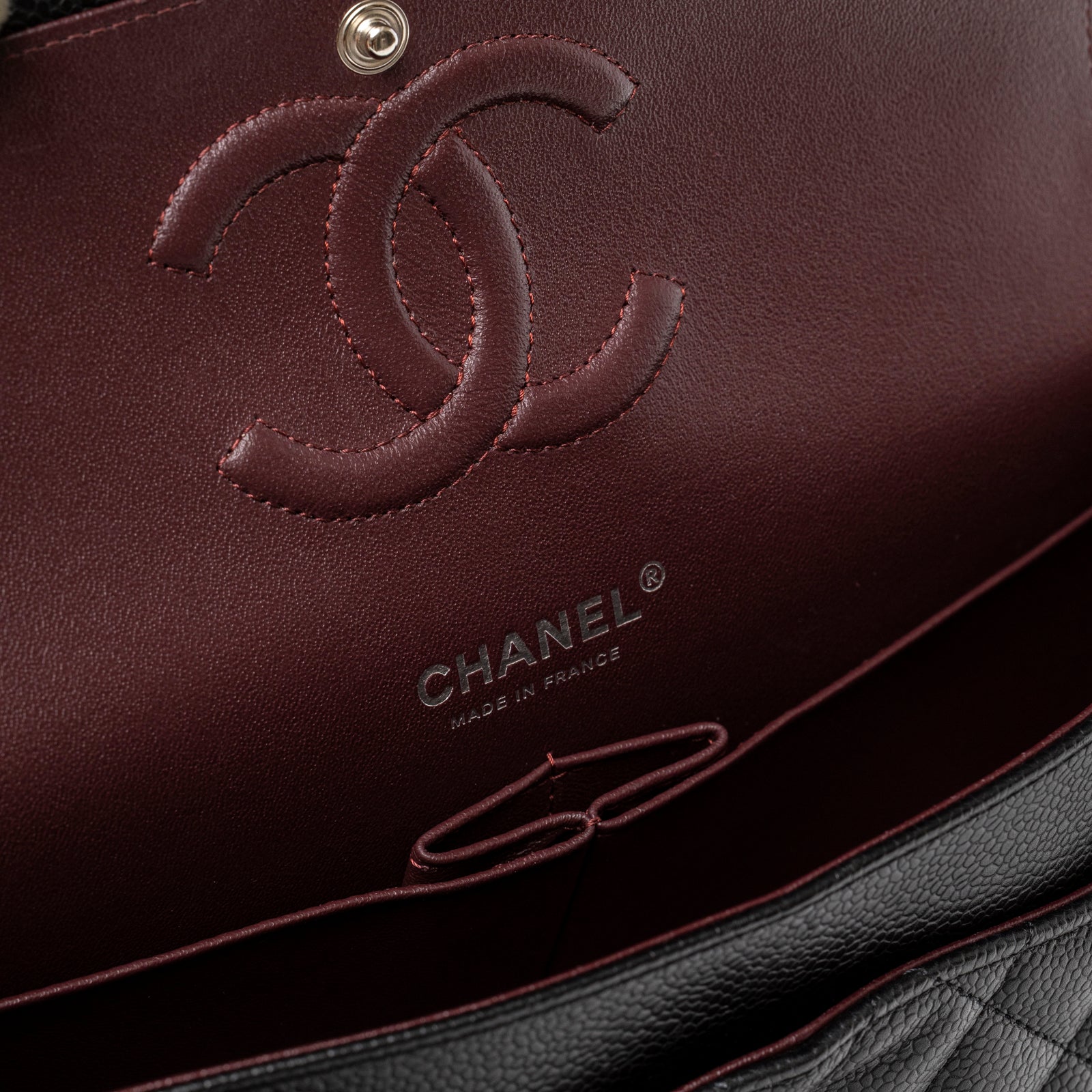 Close-up inside view of burgundy leather interior with embossed logo on Chanel Medium Classic Flap Bag Black Caviar Palladium Hardware