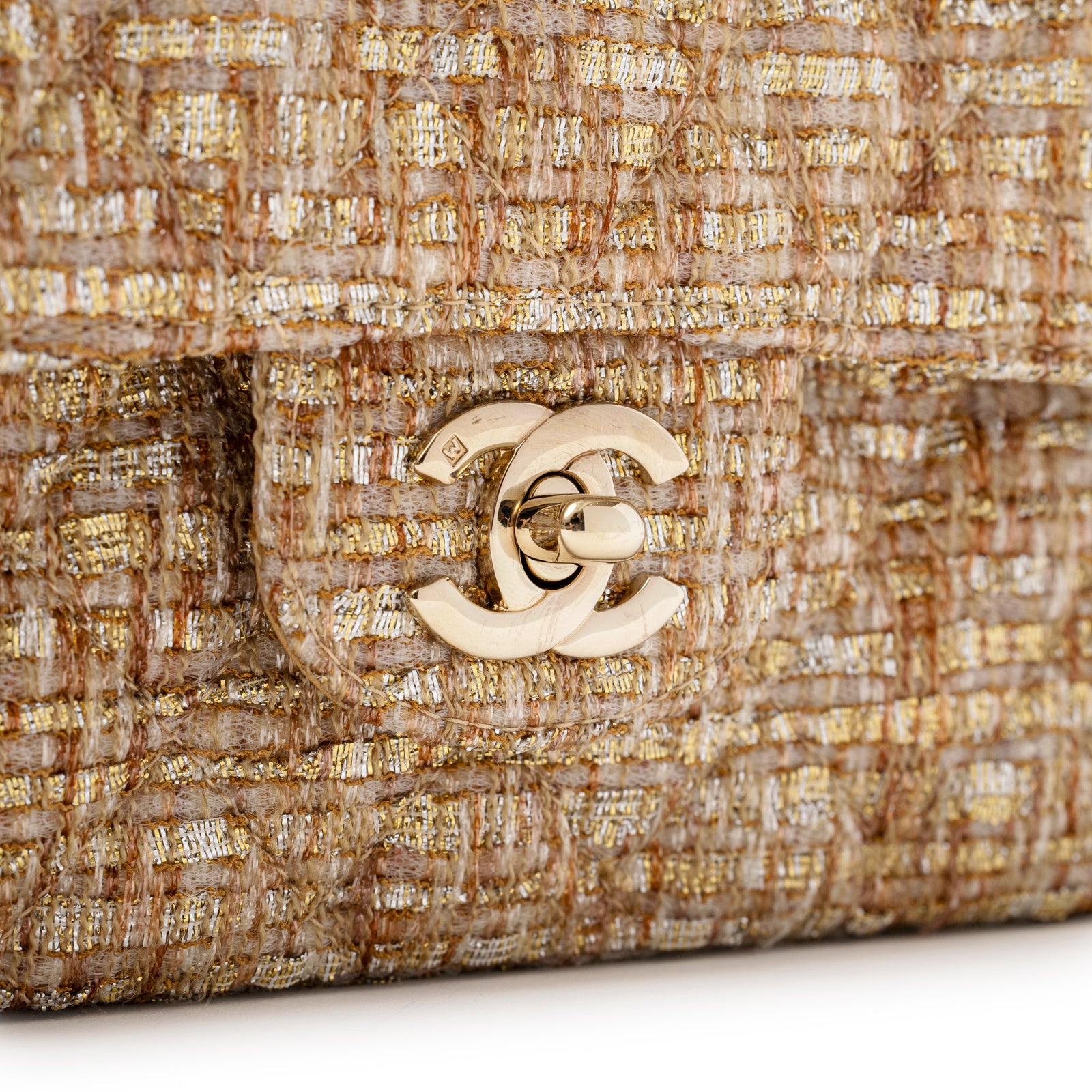 Close-up of gold hardware CC turn-lock on textured beige and gold tweed Chanel Classic Double Flap Medium Gold Beige Tweed Gold Hardware