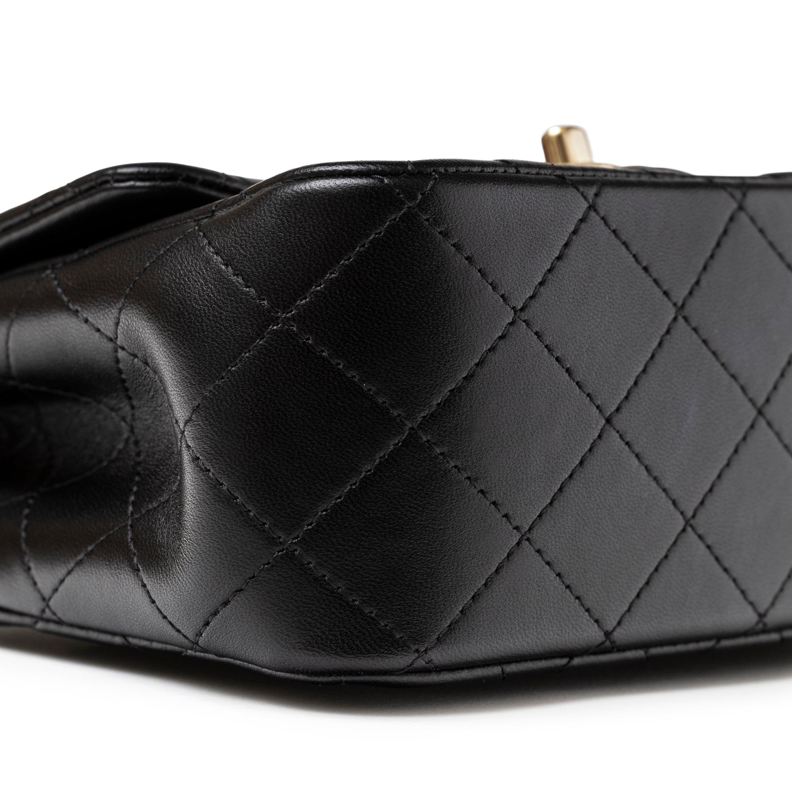 Close-up of corner quilted Black Lambskin and detailed stitching on Chanel Mini Square Classic Flap bag Black Lambskin Light Gold Hardware