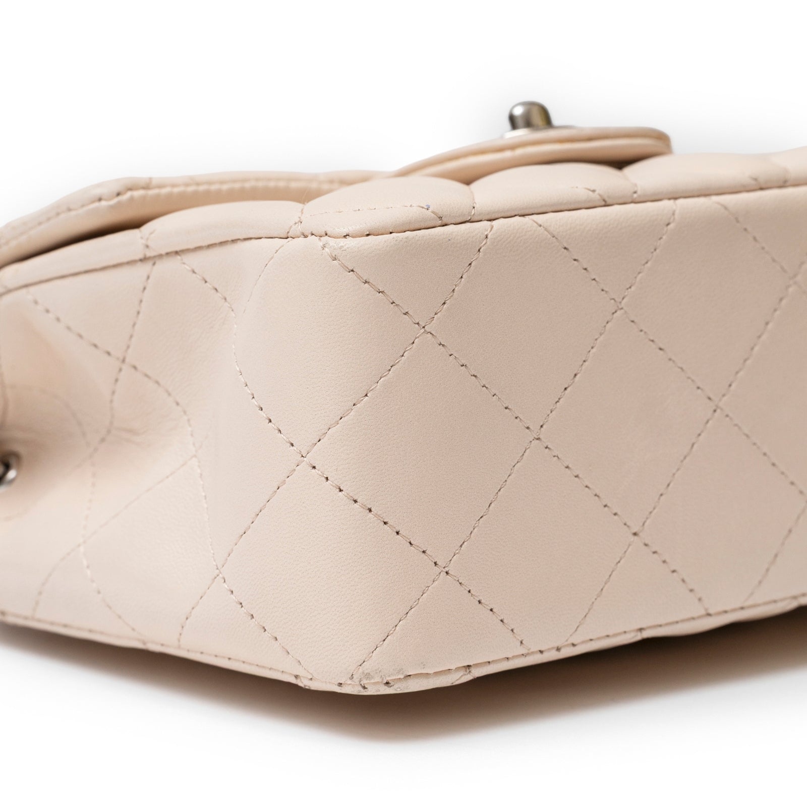 Close-up angled shot of the bottom corner stitching on Chanel Mini Square Single Flap Lambskin Beige Silver Hardware