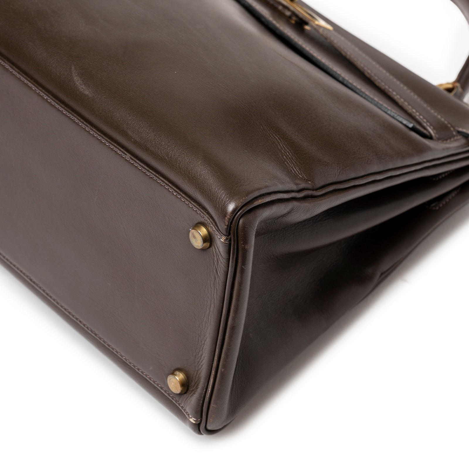 Close-up of bottom corner on Hermès 1974 Vintage Kelly 32 Marron Foncé Box Gold Hardware showing smooth leather and gold feet