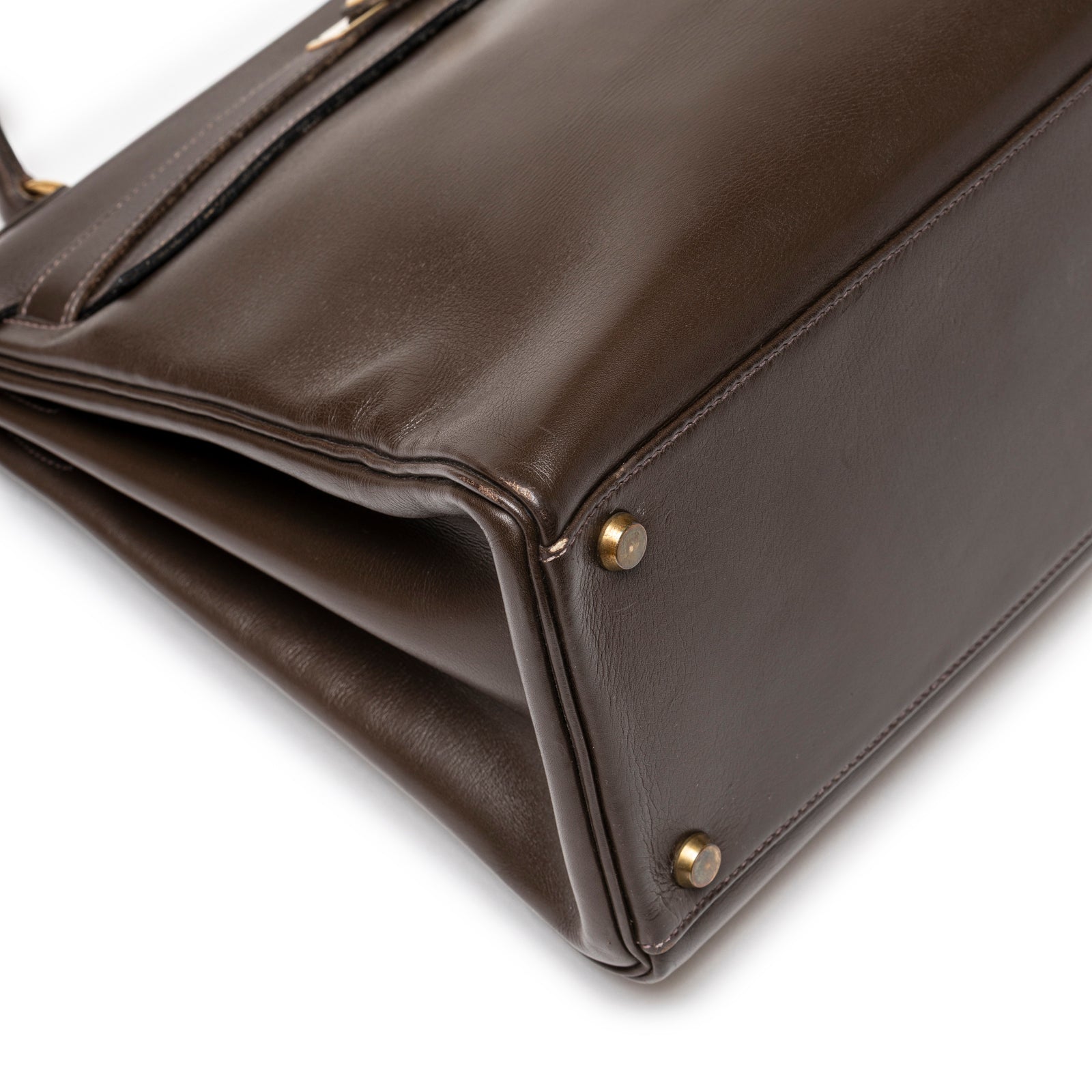 Close-up of bottom corner on Hermès 1974 Vintage Kelly 32 Marron Foncé Box Gold Hardware showing leather texture and gold feet