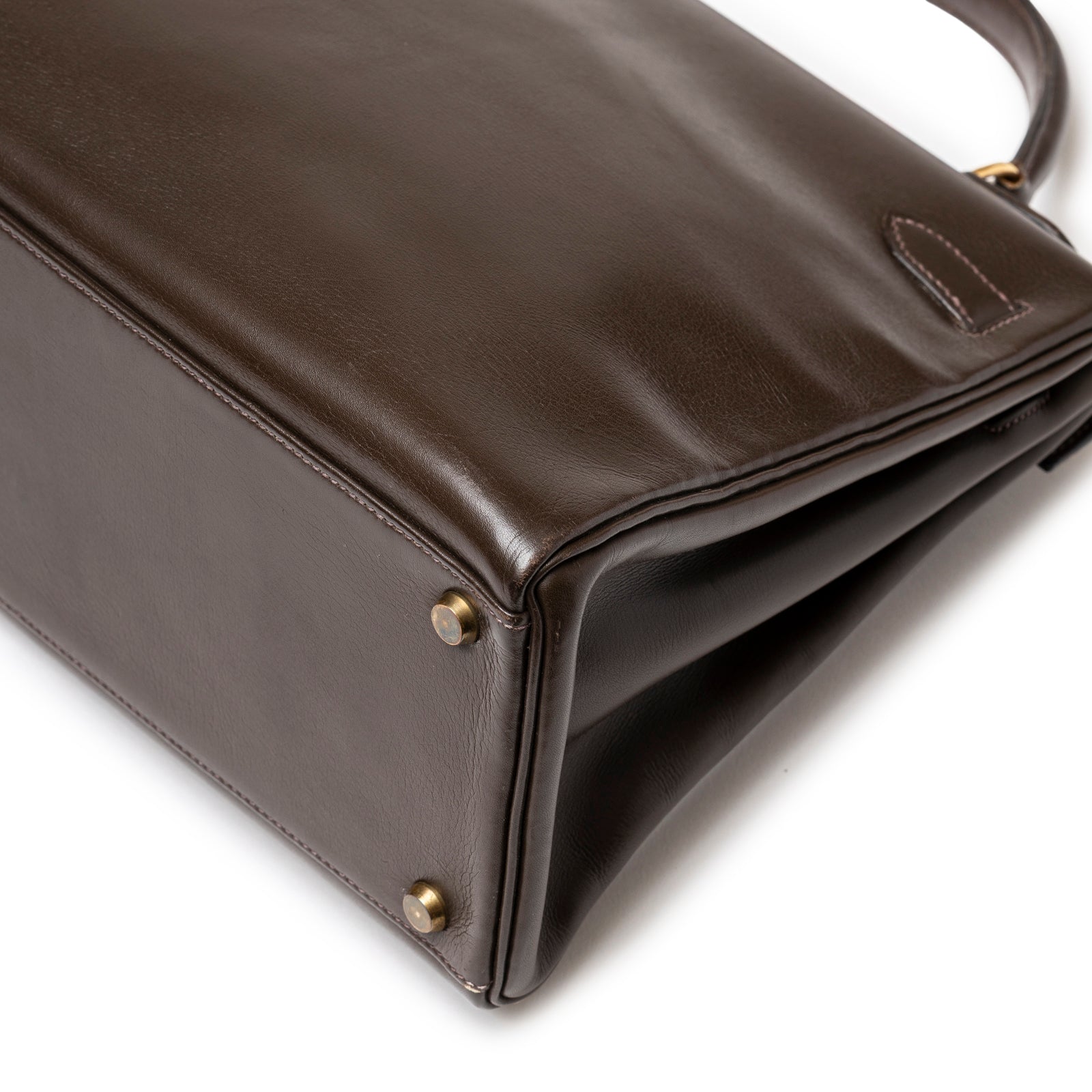 Close-up of base corner on Hermès 1974 Vintage Kelly 32 Marron Foncé Box Gold Hardware showing smooth leather and gold feet details