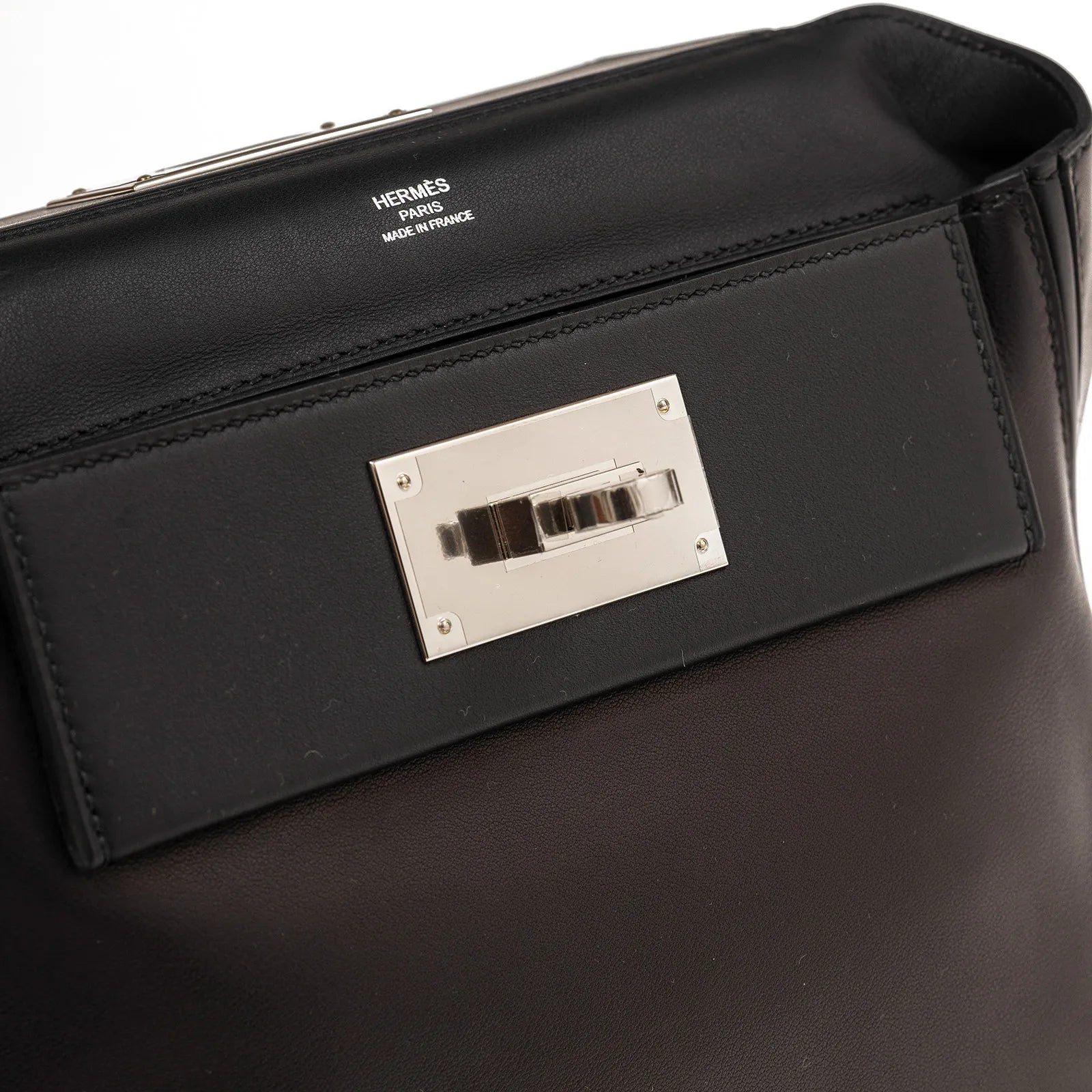 Close-up of black leather Hermès 24/24 21 handbag showing palladium hardware clasp and embossed interior logo