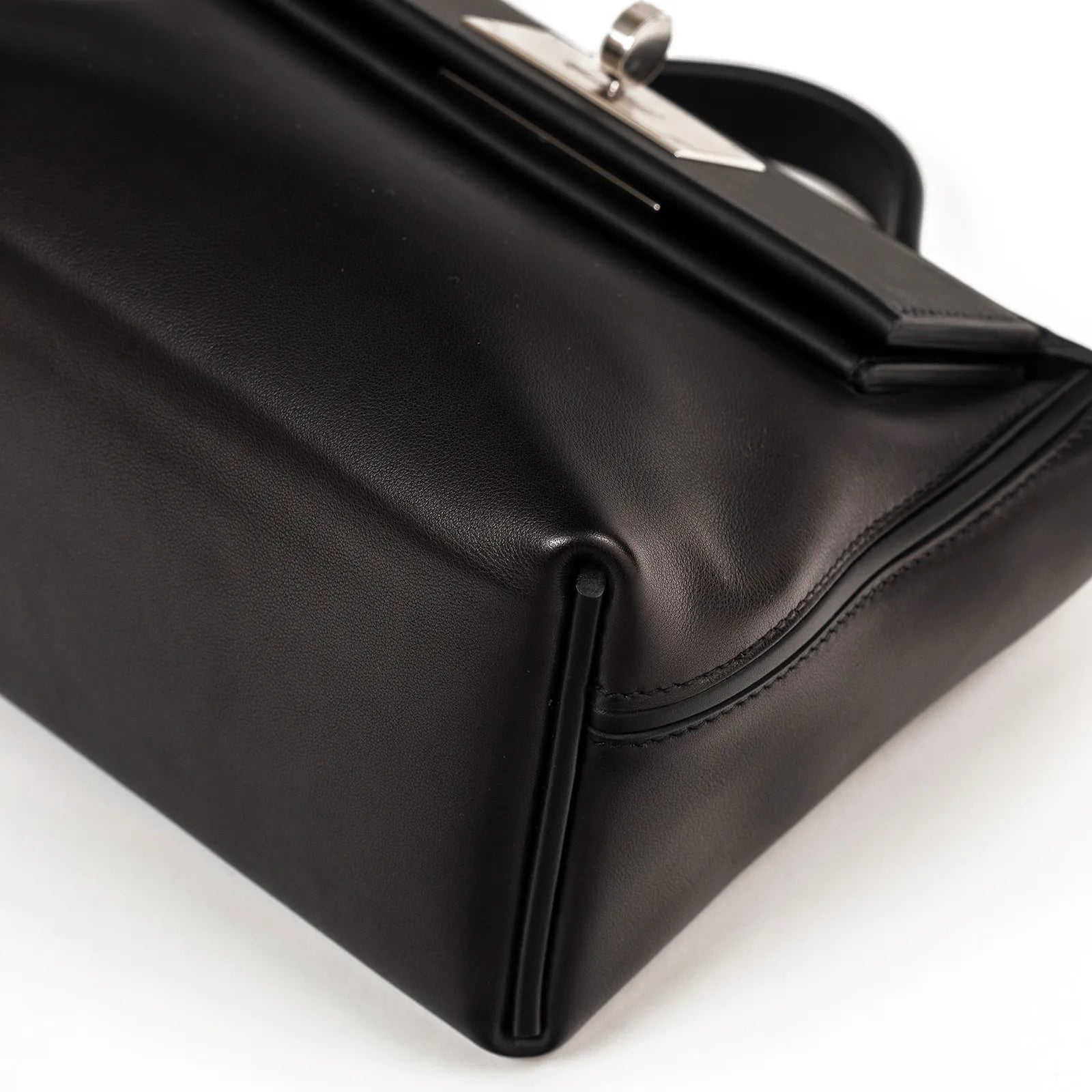 Close-up angled shot of black Volupto leather with smooth stitching and palladium hardware corner details