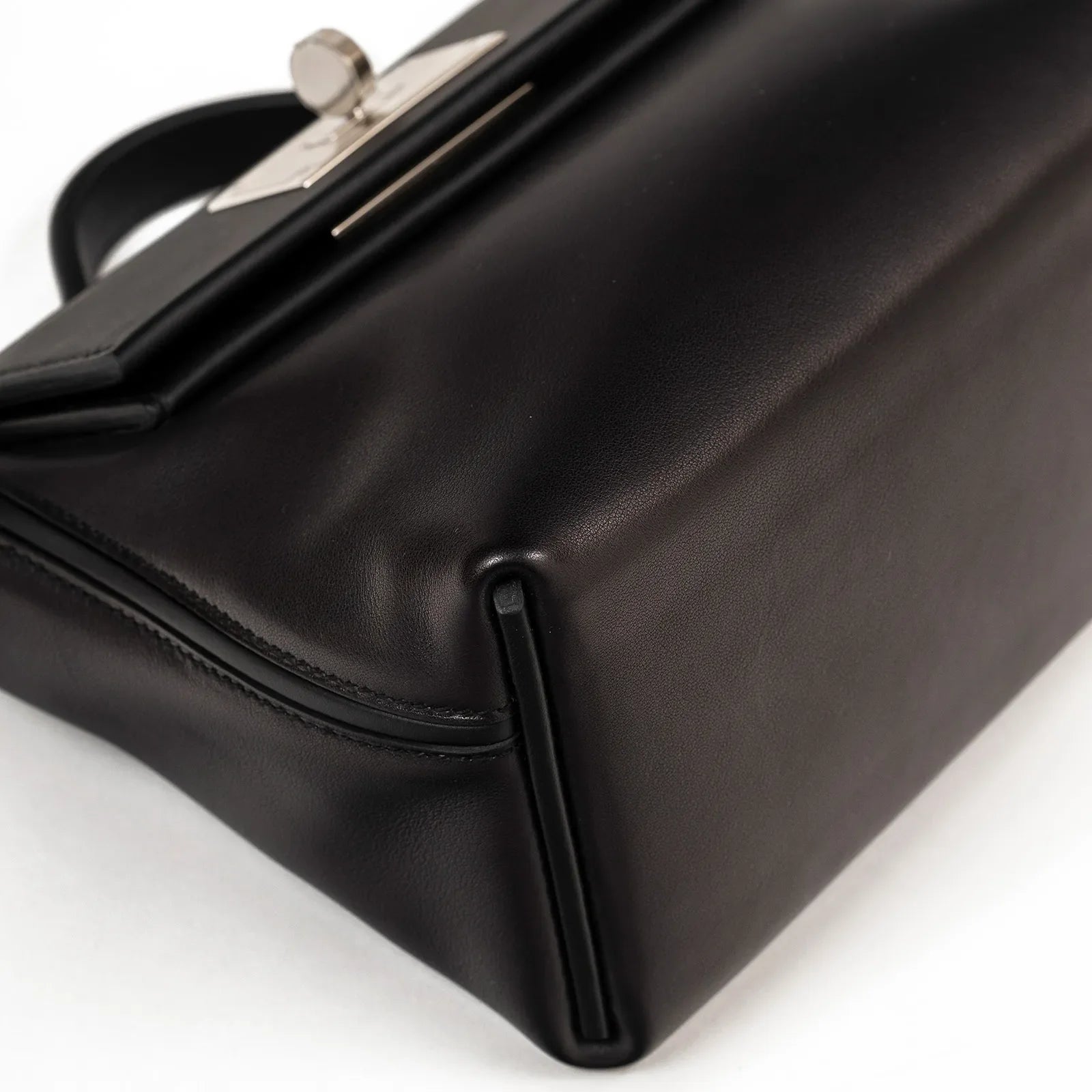 Close-up angled view of black leather Hermès 24/24 21 showcasing smooth surface and palladium hardware details