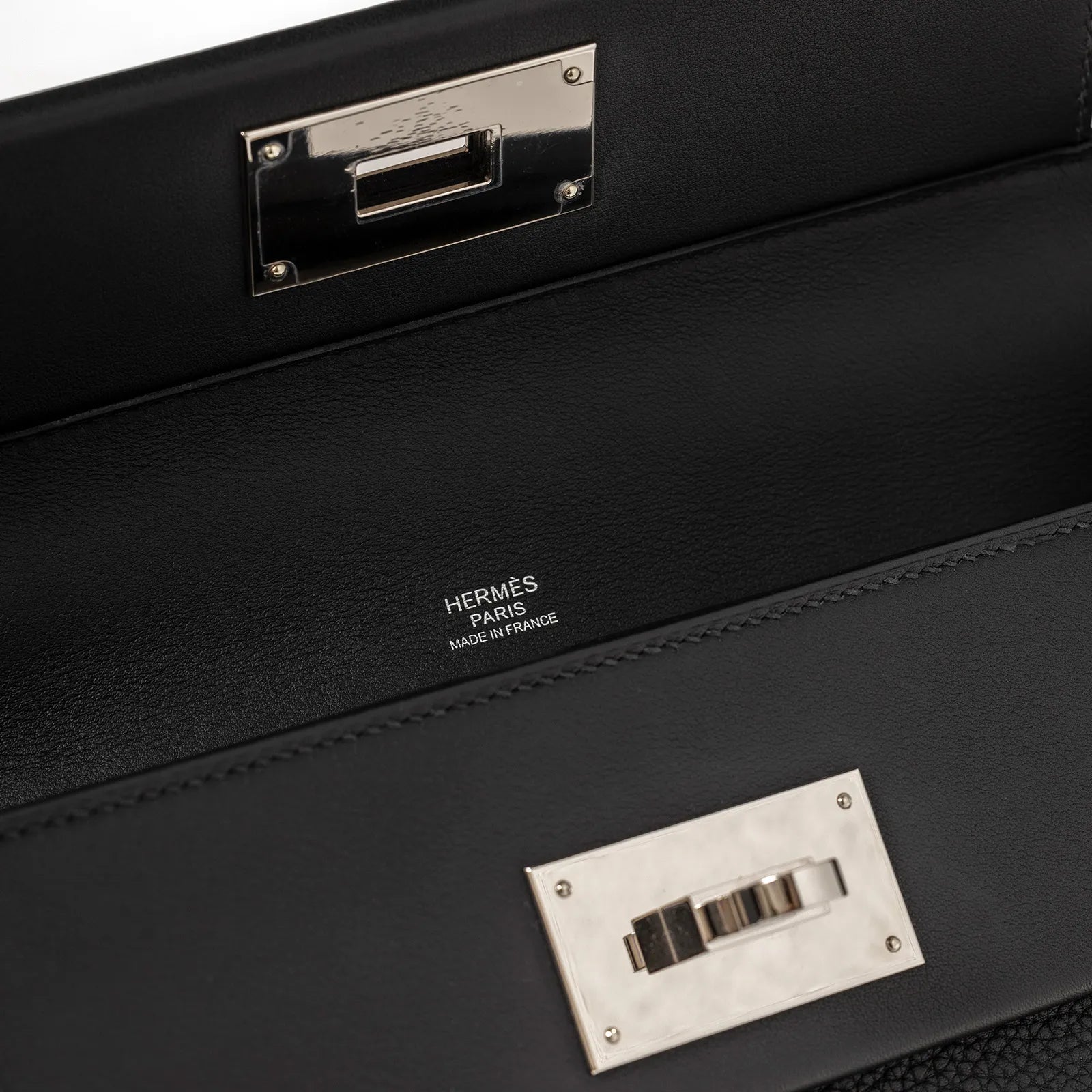 Close-up of black Taurillon Maurice leather interior showing Hermès Paris stamp and palladium hardware clasp detail