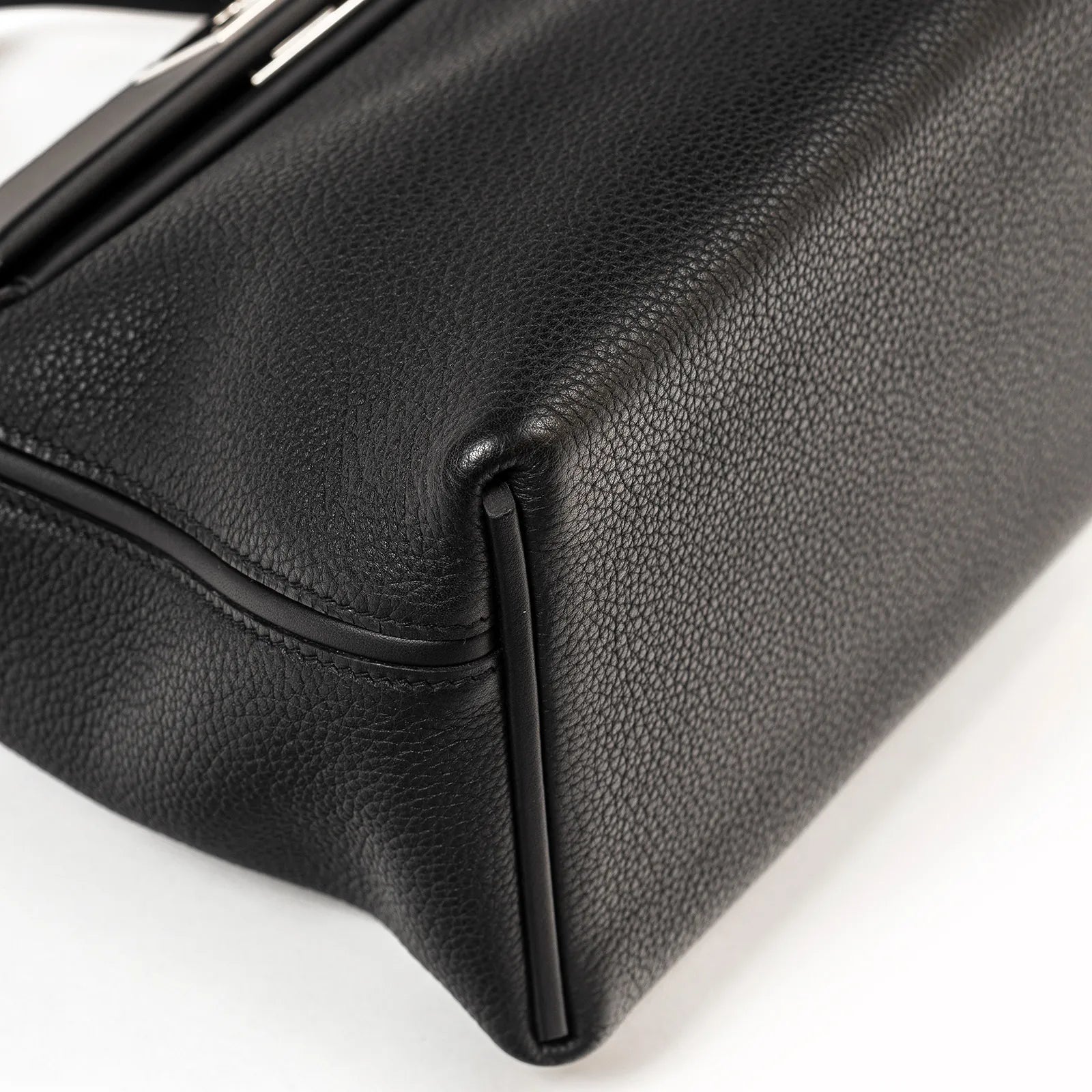 Close-up of black Taurillon Maurice leather corner with smooth piping and fine grain texture on sac bag bottom edge