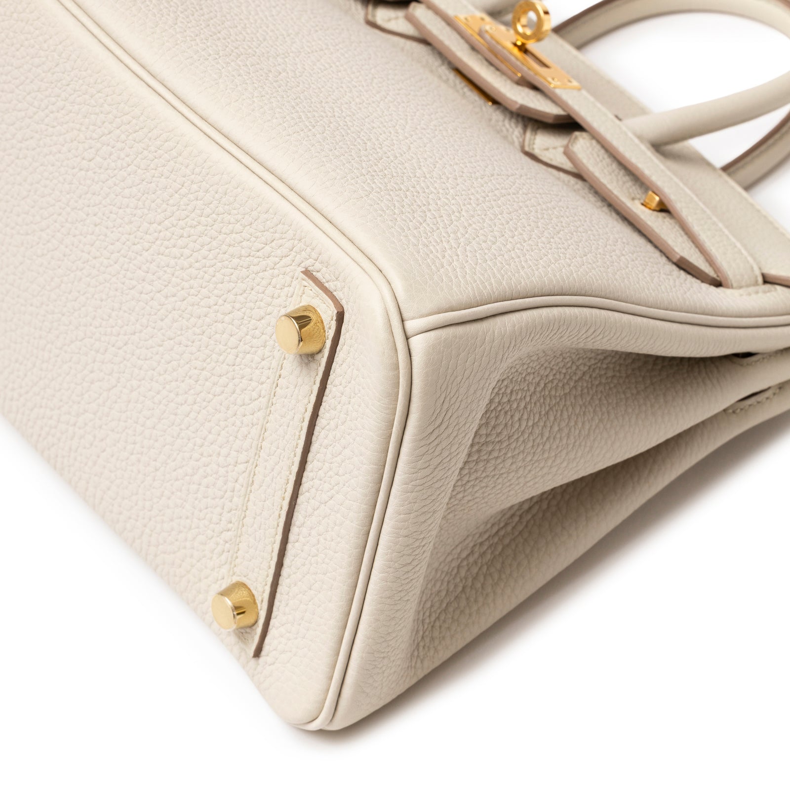 Close-up of base corner and gold hardware feet on Hermès Birkin 25 Beton Togo Gold Hardware handbag.