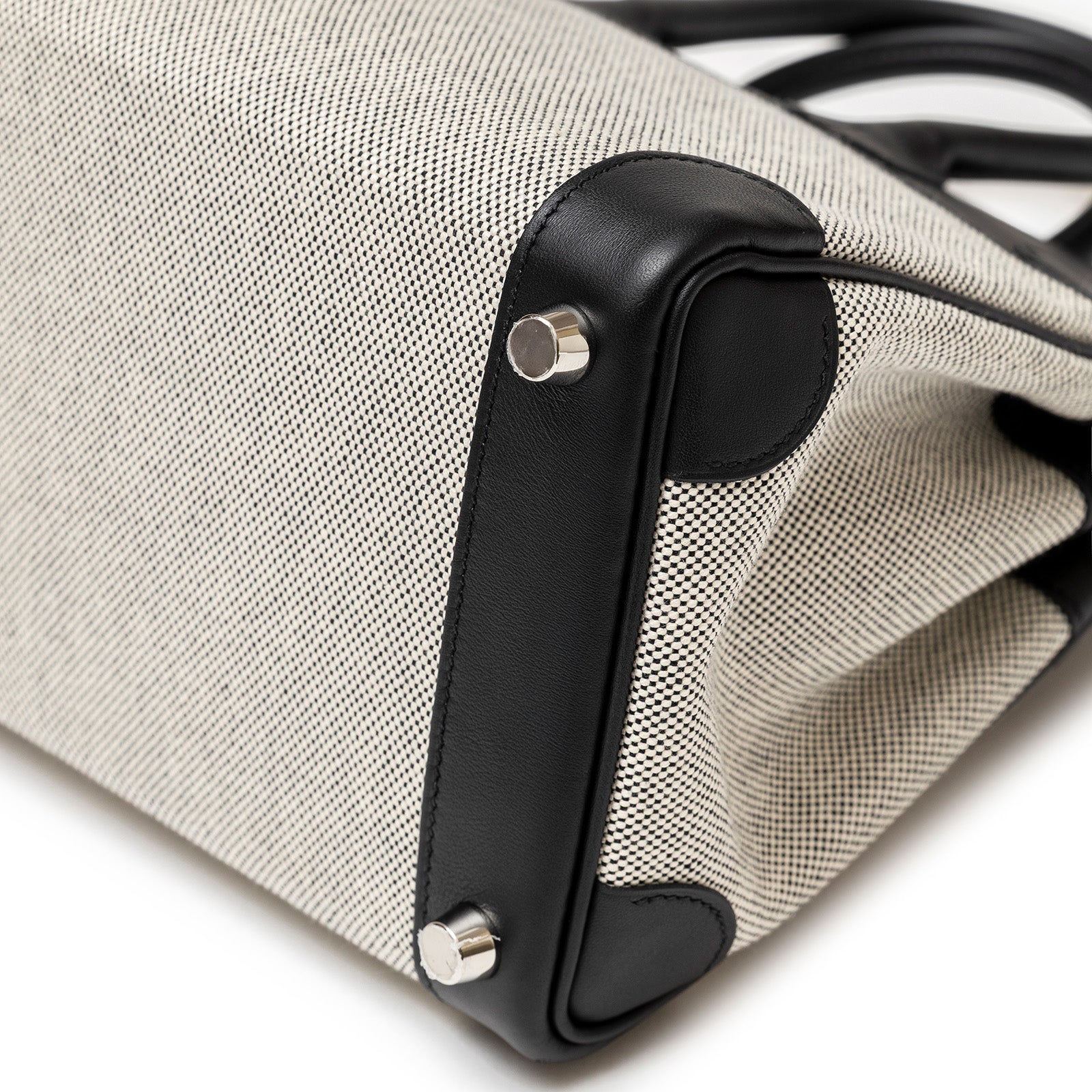 Close-up of bottom corner and palladium hardware of Hermès Birkin 25 Black Swift/Ecru Toile H Canvas Palladium Hardware by Hermès