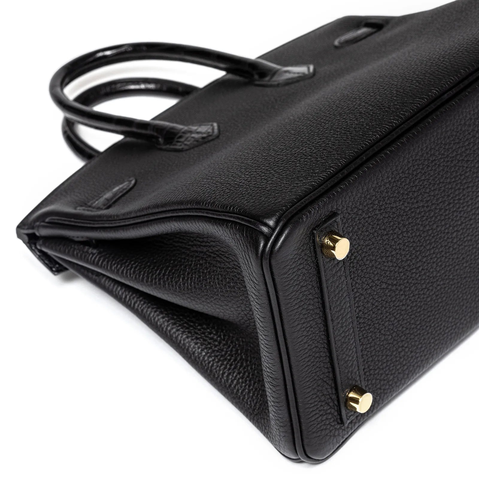Angled bottom view of Hermès Birkin 25 in black Togo leather with gold hardware and rolled handles visible