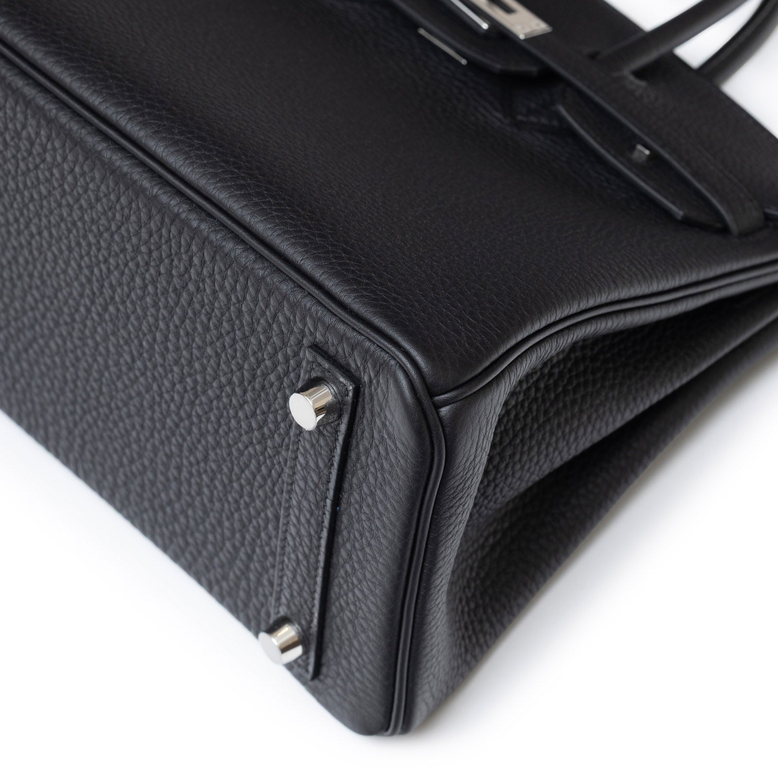 Close-up angled shot of Hermès Birkin 25 Black Togo Palladium Hardware showing textured leather and metal feet details