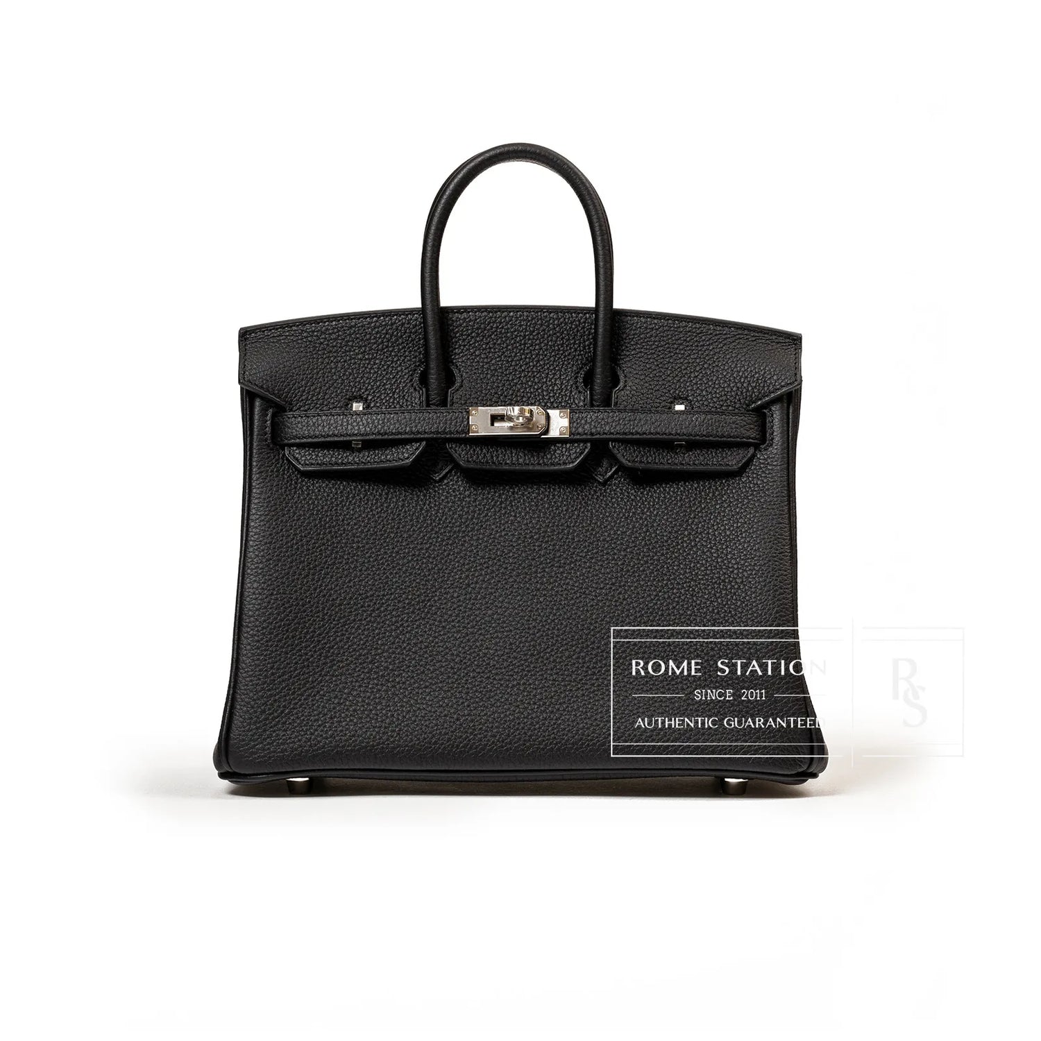 Front view of black Togo leather handbag with palladium hardware and structured top handles on white background
