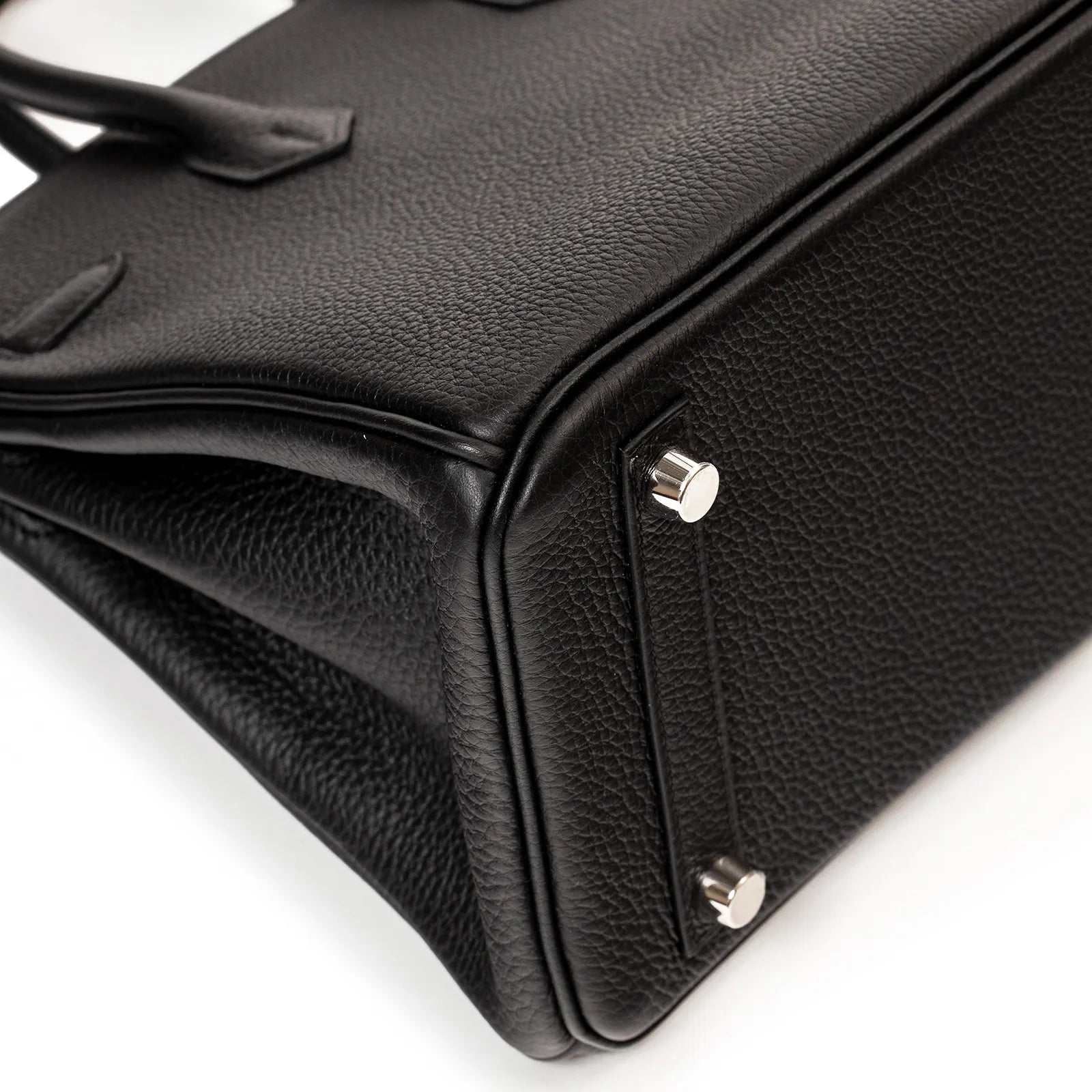 Close-up angled view of black Togo leather Birkin 25 corner showing palladium feet and textured finish