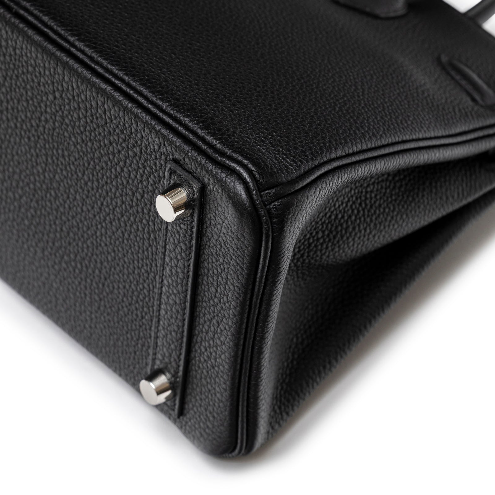 Close-up bottom angle of Hermès Birkin 25 Black Togo Palladium Hardware highlighting leather grain and metal feet details