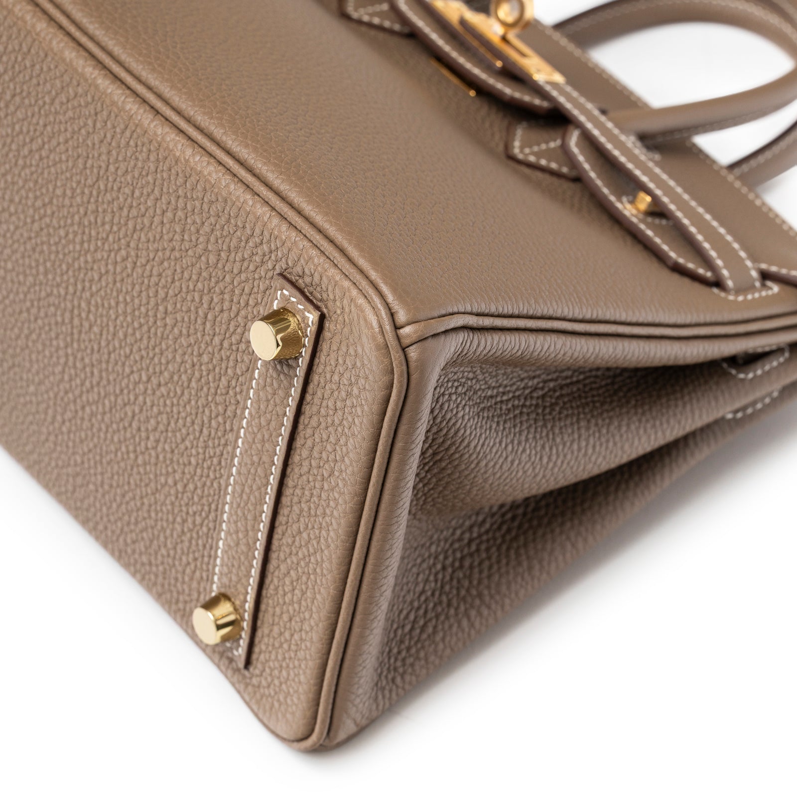 Close-up of base corner showing pebbled leather texture and gold feet on Hermès Birkin 25 Etoupe Togo Gold Hardware