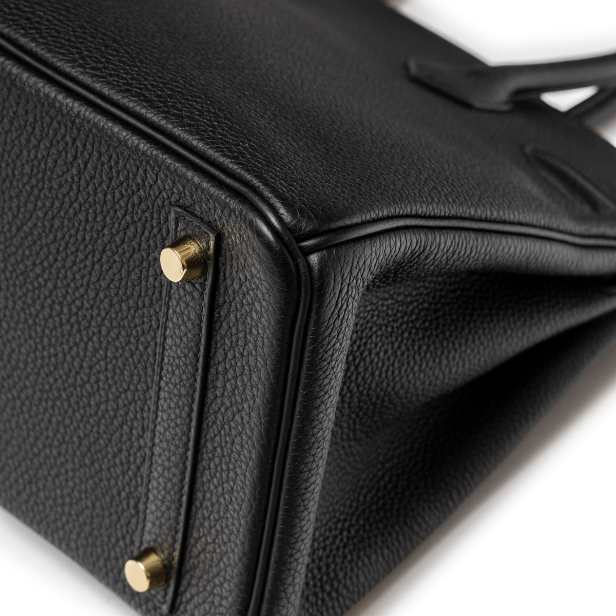 Close-up of Hermès Birkin 30 Black Togo Gold Hardware showing pebbled leather texture and gold protective feet on base corner