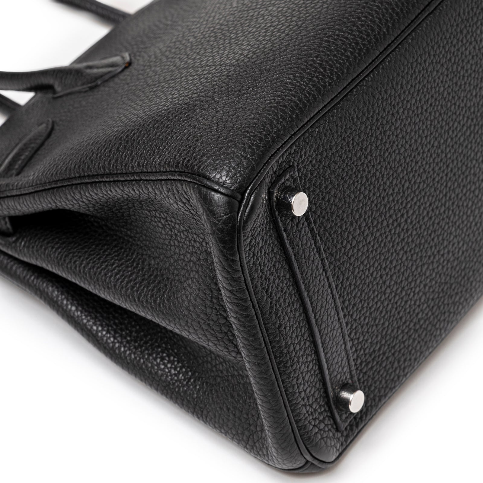 Close-up angled view of Hermès Birkin 30 Black Togo Palladium Hardware showing textured leather and metal feet detail.