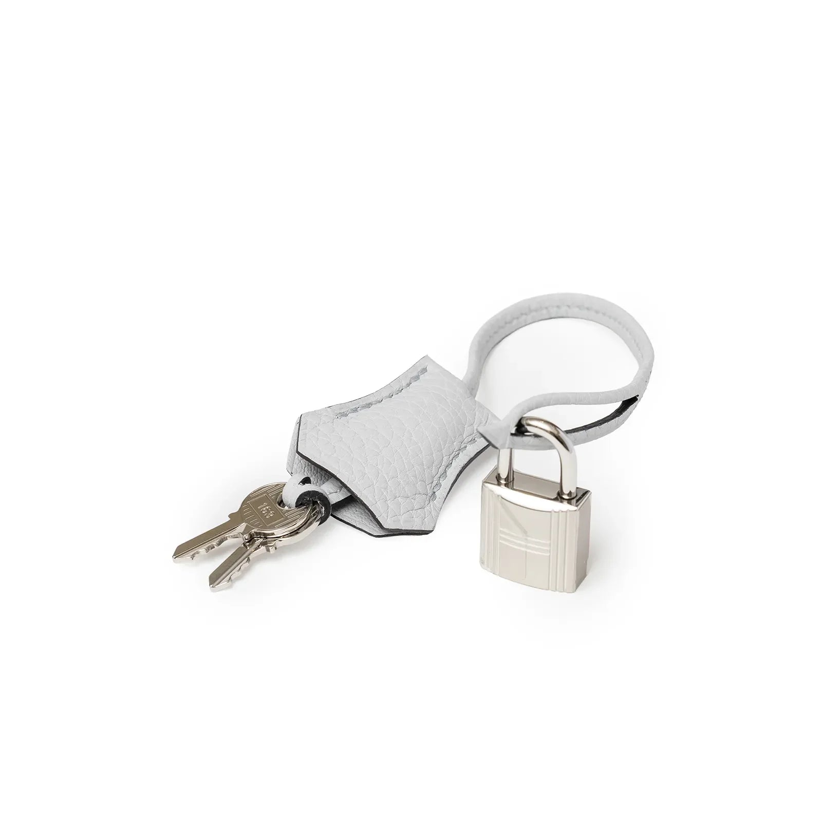 Close-up of white Clemence leather clochette with two keys and palladium lock on white background