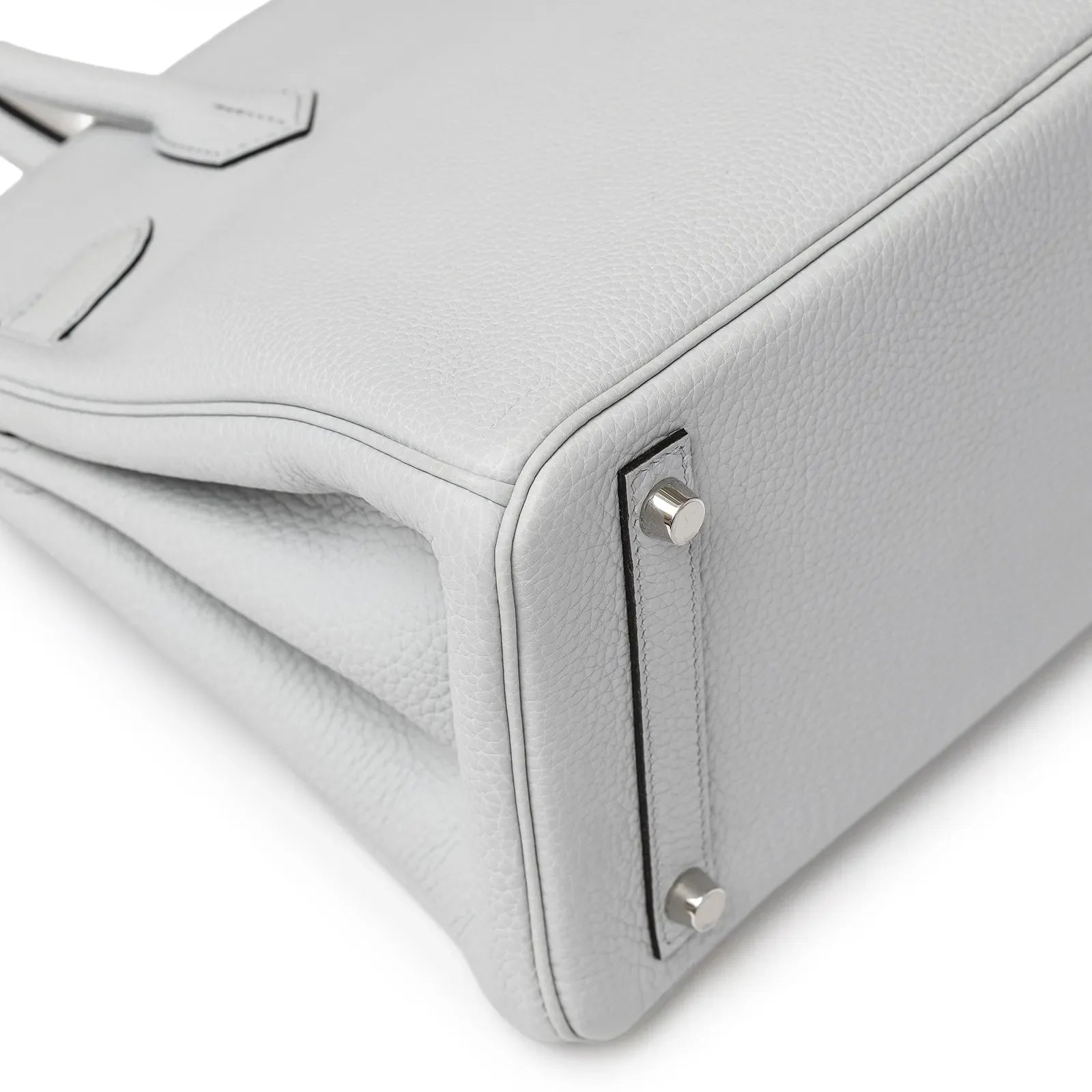 Close-up of the bottom corner of Hermès Birkin 30 in pale blue Clemence leather with palladium hardware feet.