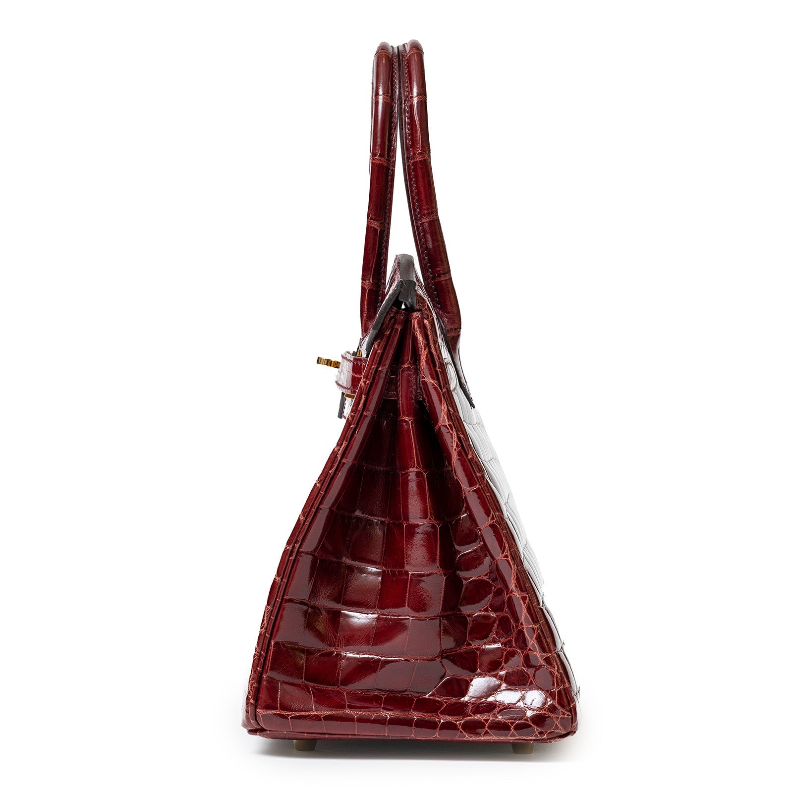 Side profile of Hermès Birkin 30 in shiny Bourgogne Niloticus crocodile with gold hardware and double handles
