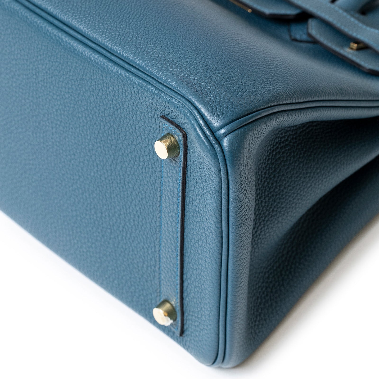 Close-up bottom corner view of Hermès Birkin 30 Colvert Togo leather with gold hardware and protective feet.