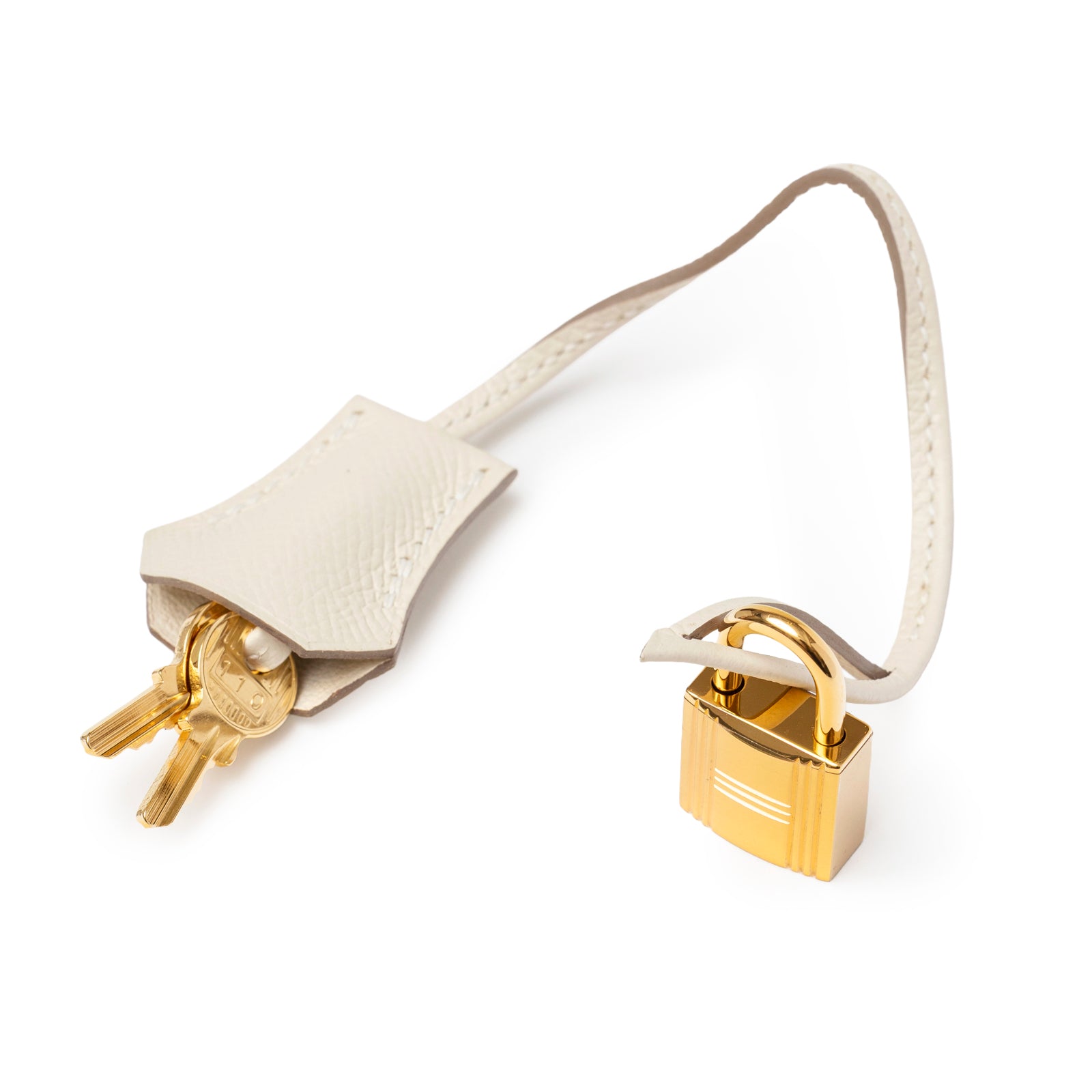 Close-up of Hermès Birkin 30 Craie Epsom Gold Hardware gold lock and keys on cream textured leather strap.