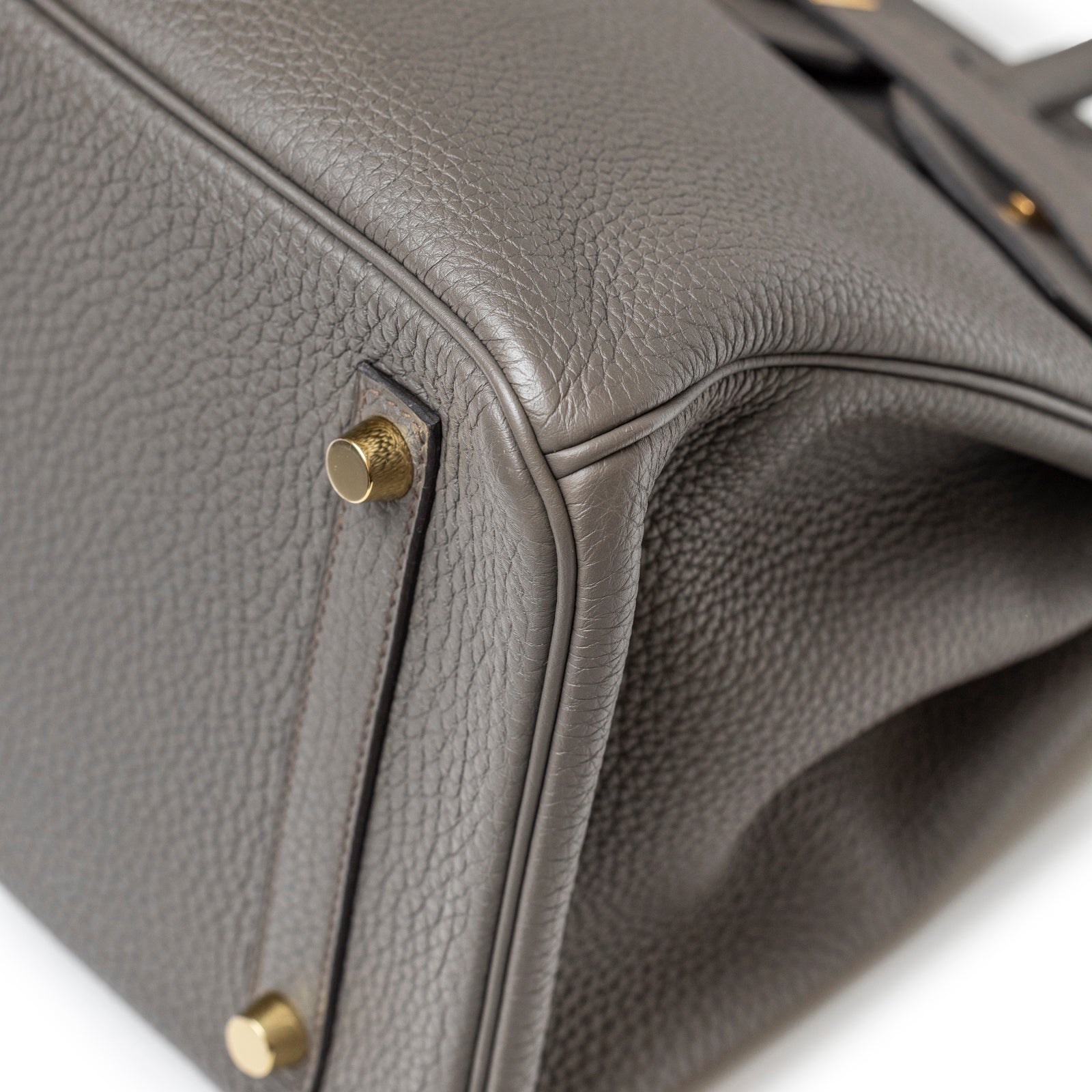 Close-up angled shot of Hermès Birkin 30 Gris Meyer Togo Gold Hardware showing textured leather and gold feet detail.