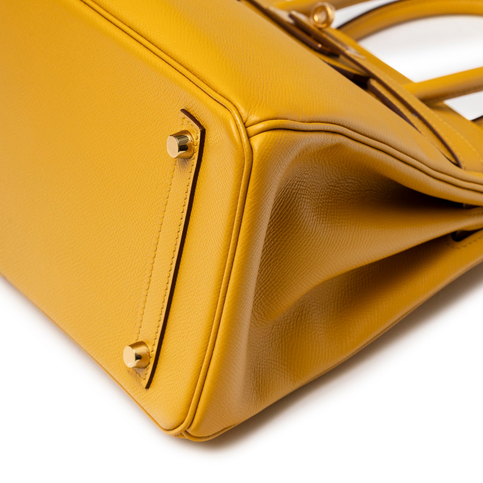 Close-up of base and side corner of Hermès Birkin 30 Jaune Ambre Epsom Gold Hardware showing textured leather and hardware studs