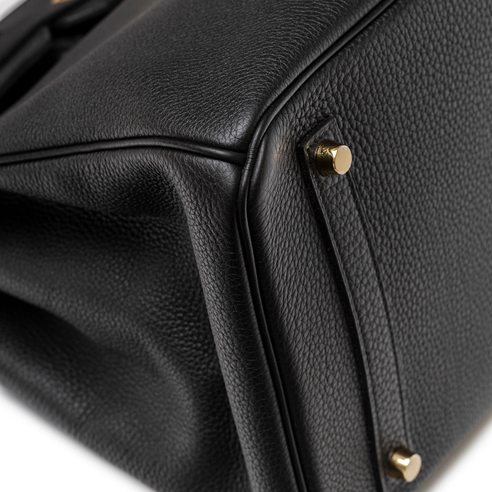 Close-up of Hermès Birkin 35 Black Togo Gold Hardware showing grain texture and gold metal studs on the base