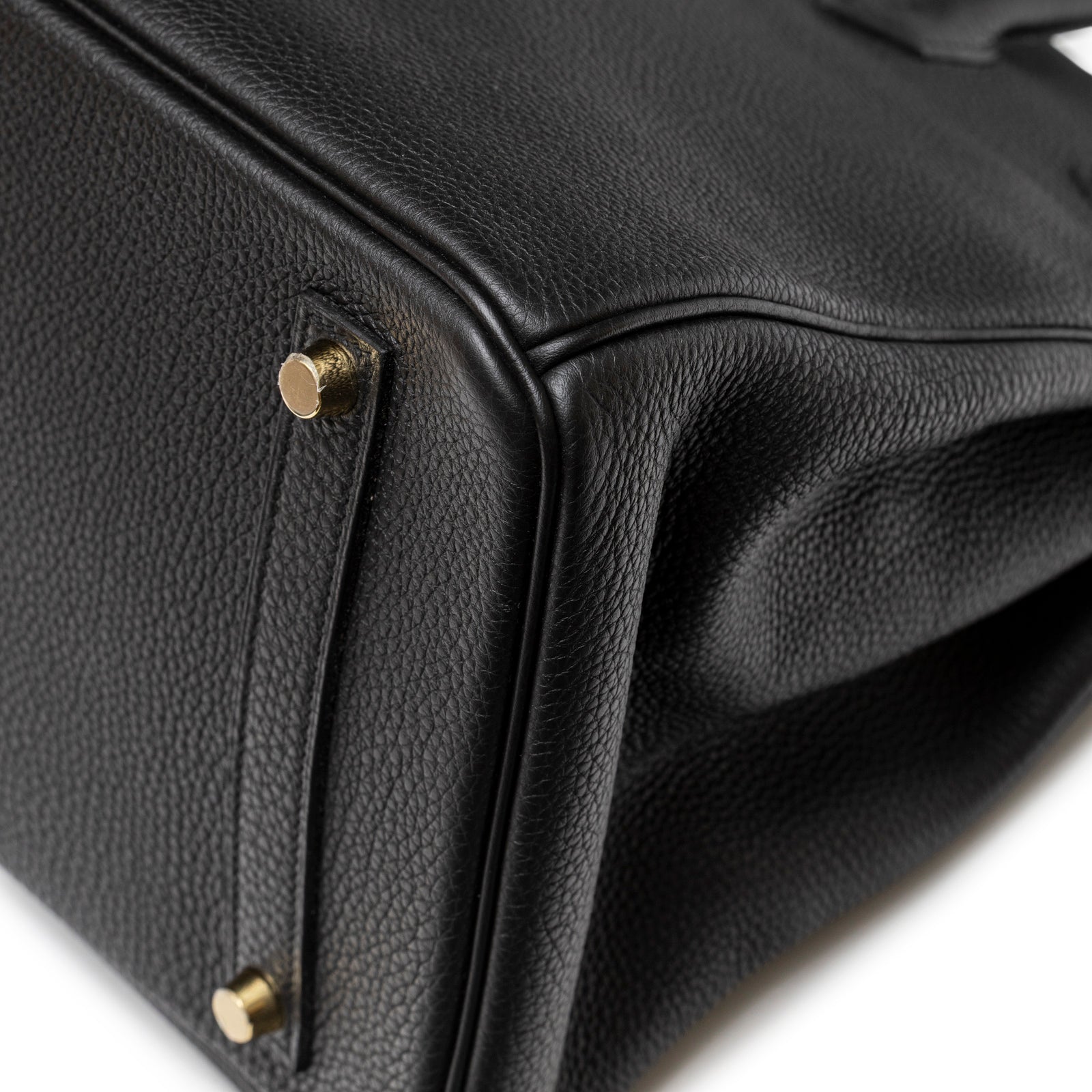 Close-up of bottom corner showing textured black Togo leather and gold hardware on Hermès Birkin 35 Black Togo Gold Hardware.