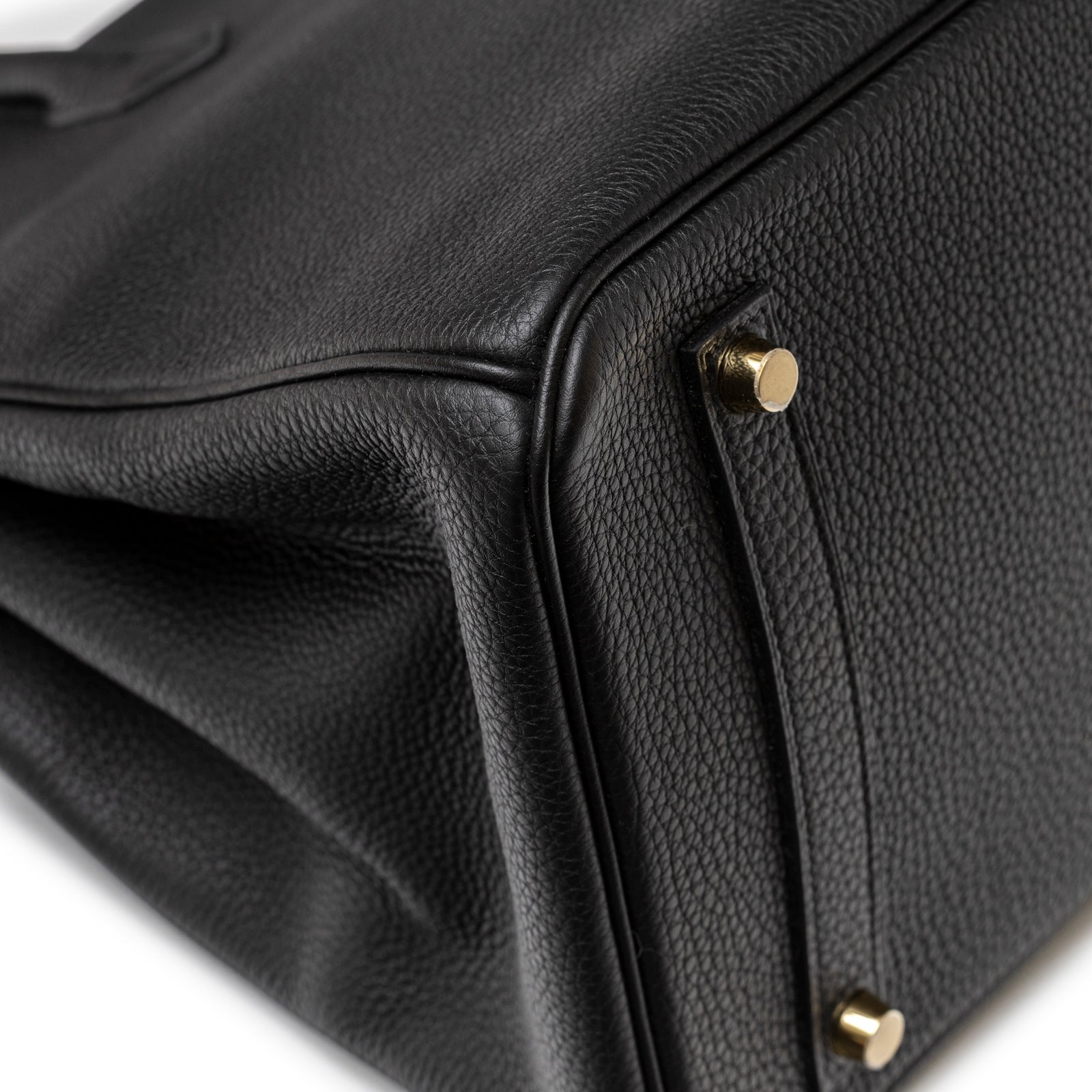Close-up of Hermès Birkin 35 Black Togo Gold Hardware corner showing textured leather and gold studs feet detail.