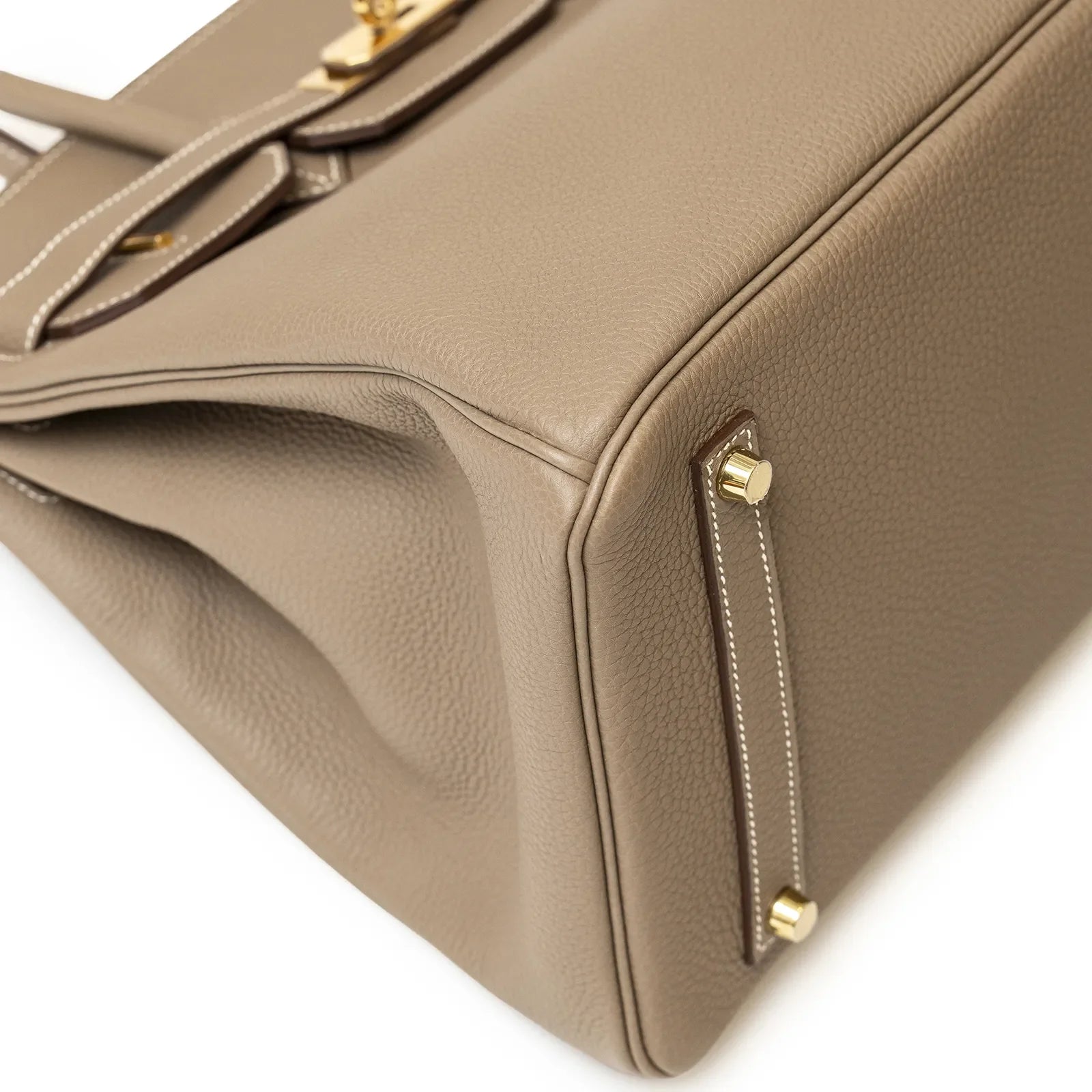 Close-up of Hermès Birkin 35 Etoupe Togo leather showing gold hardware and bottom corner stitching detail.