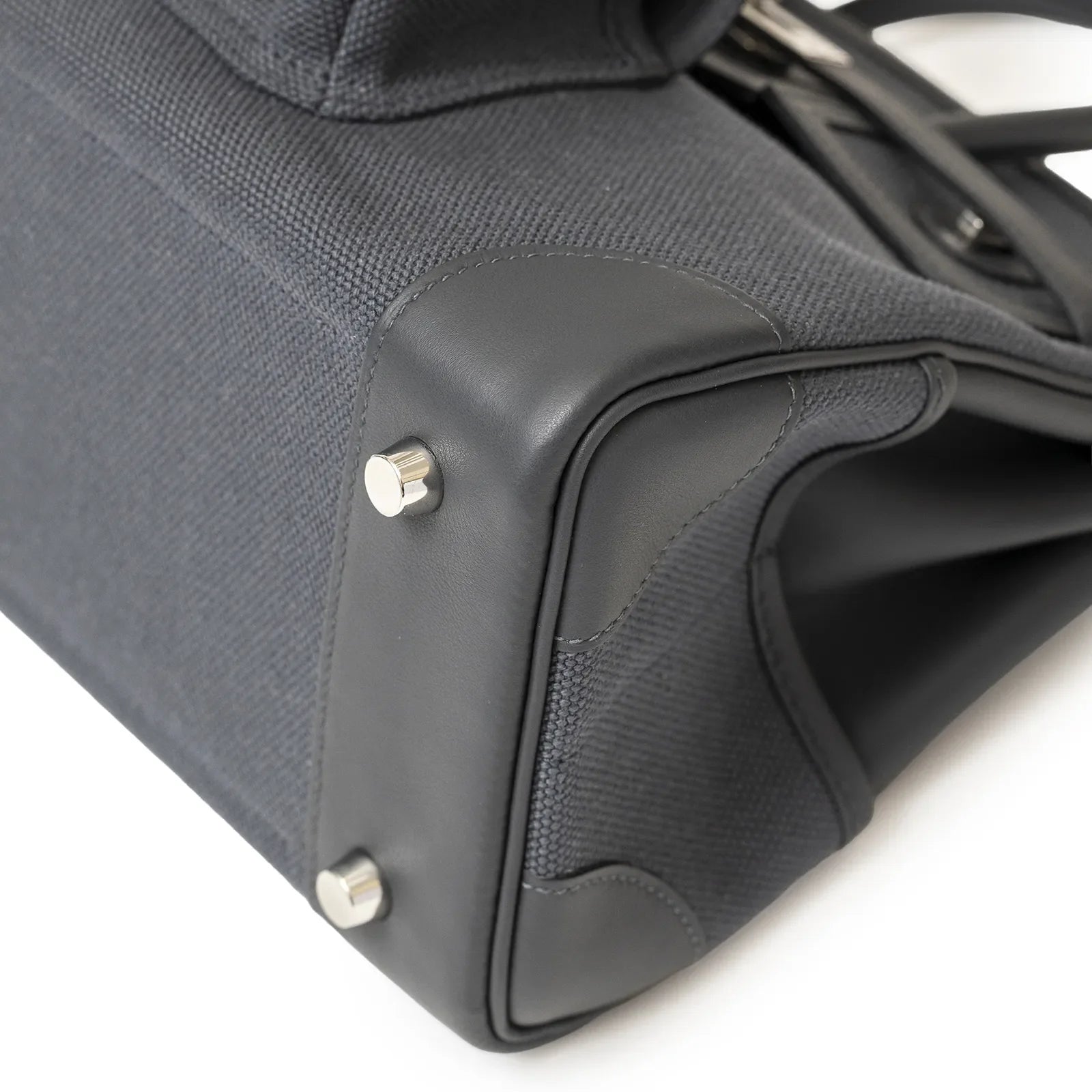 Close-up of bottom corner showing palladium hardware and grey canvas with black Swift leather trim on bag
