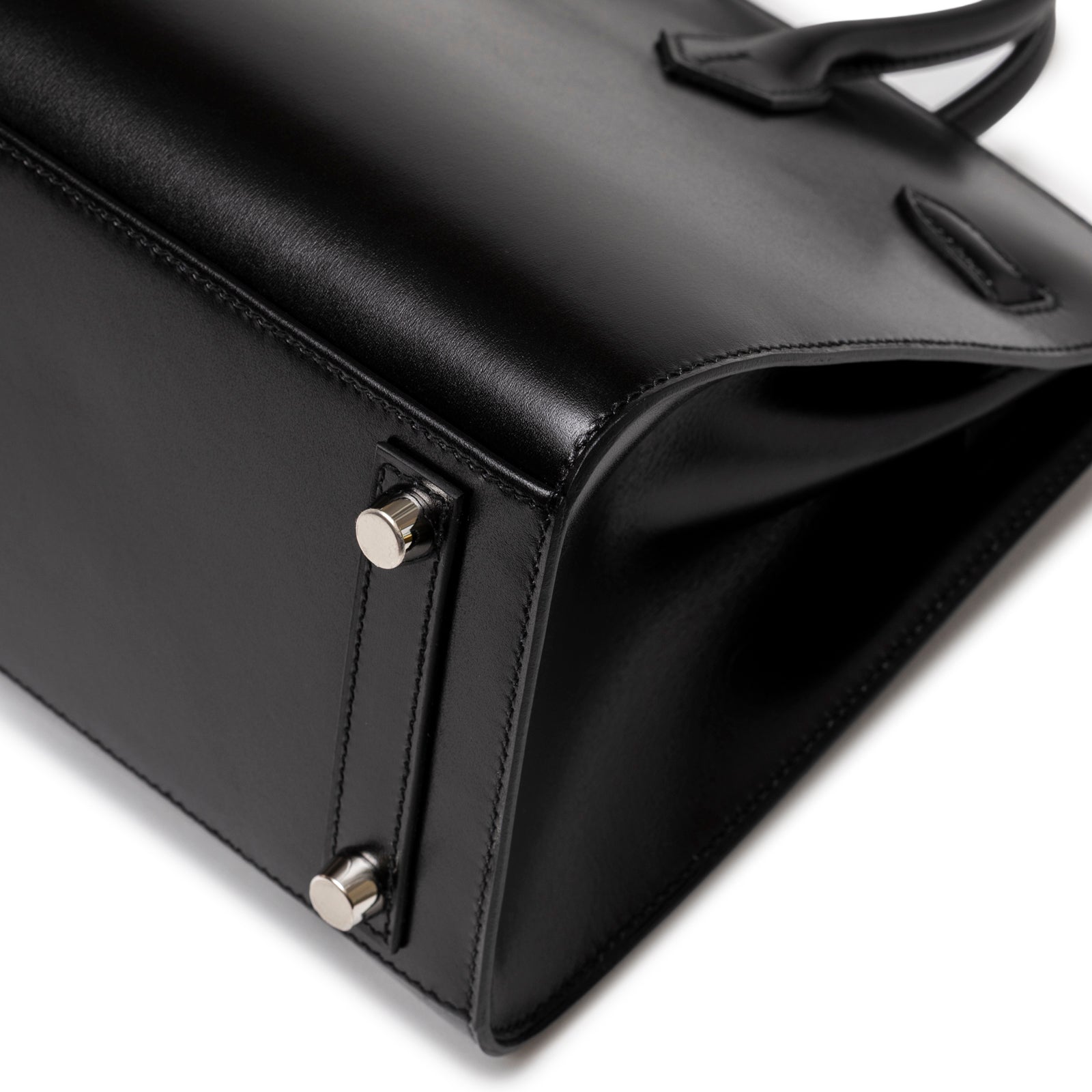 Close-up of bottom corner showing smooth black leather and palladium hardware feet on Hermès Birkin Sellier 25 Black Box Palladium Hardware