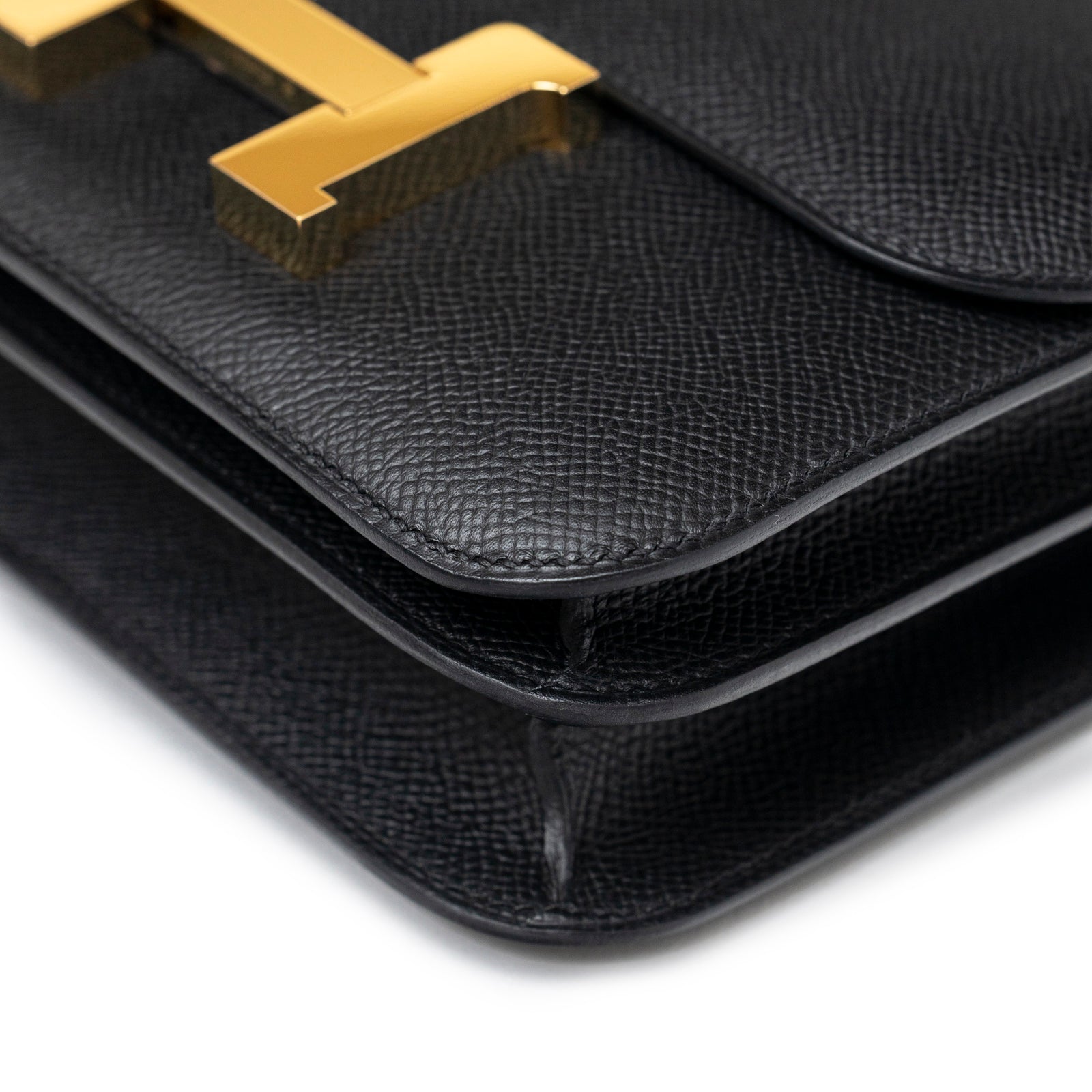 Close-up angled shot of Hermès Constance 18 Black Epsom Gold Hardware showing textured leather and clasp detail