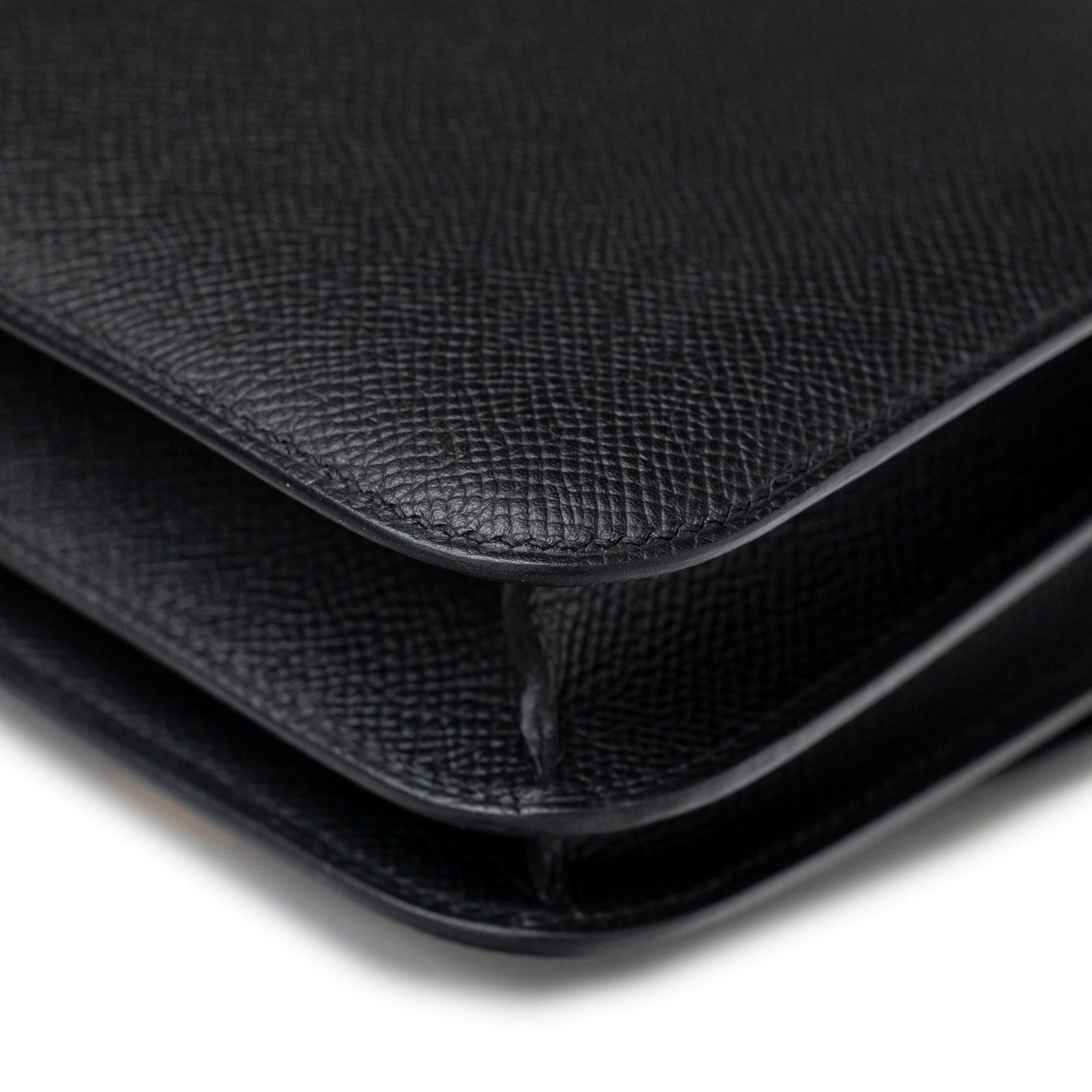 Close-up angled view of Hermès Constance 18 Black Epsom Gold Hardware showing black textured leather edges