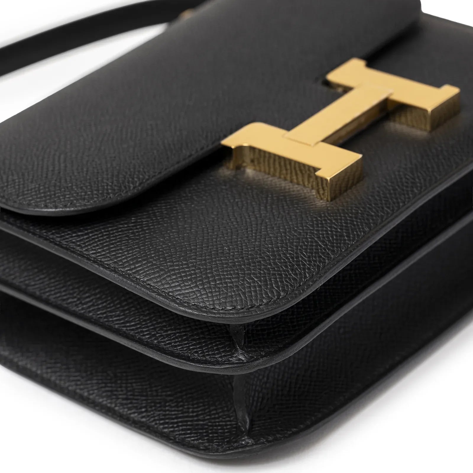 Close-up angled view of Hermès Mini Constance 18 Black Epsom Gold Hardware showing texture and clasp detail