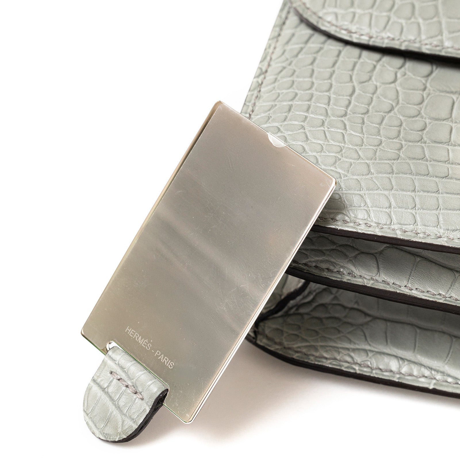 Close-up of gold hardware clasp on Hermès Mini Constance 18 Gris Ciment Matte Alligator bag showing texture and detail