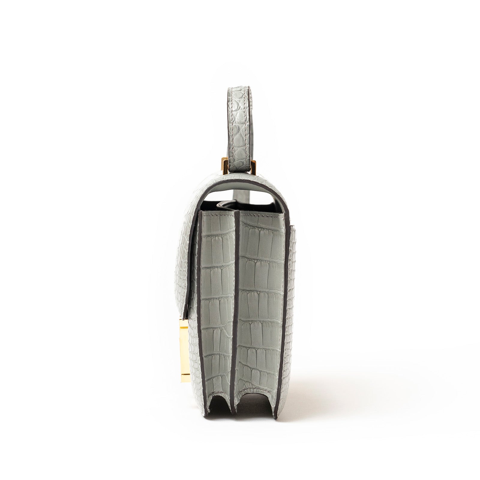 Side view of Hermès Mini Constance 18 Gris Ciment Matte Alligator Gold Hardware showing slim profile and texture details