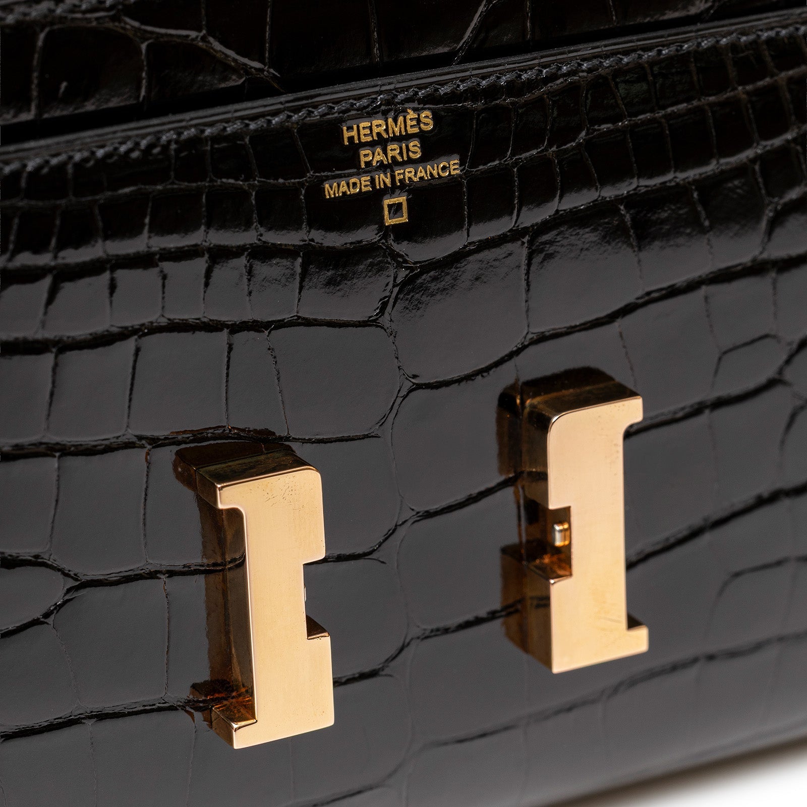 Close-up of Hermès Constance Long Wallet Black Shiny Alligator Rose Gold Hardware showing logo and gold clasp details
