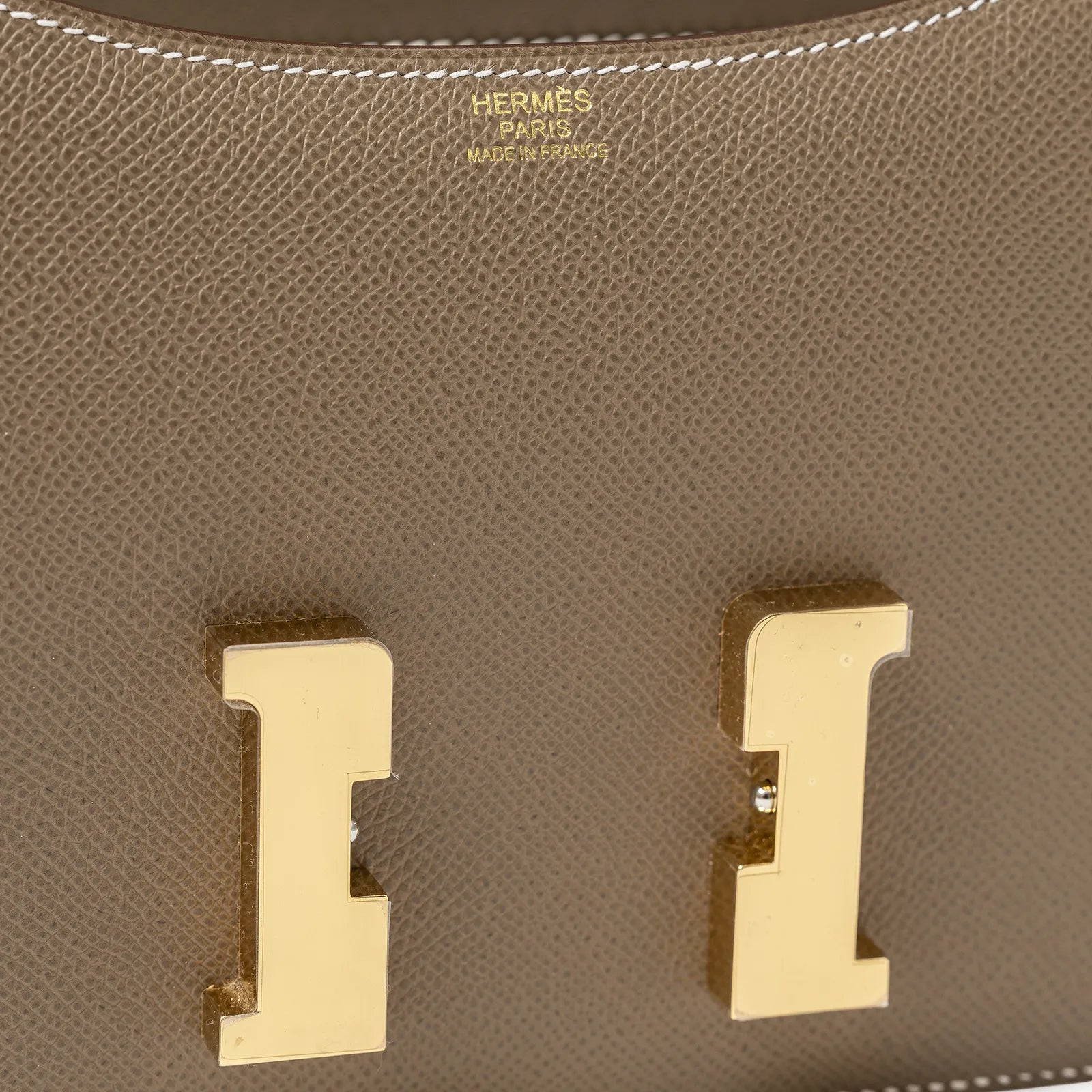 Close-up of gold hardware and Hermès Paris stamp on Hermès Constance 24 Etoupe Epsom Gold Hardware leather flap