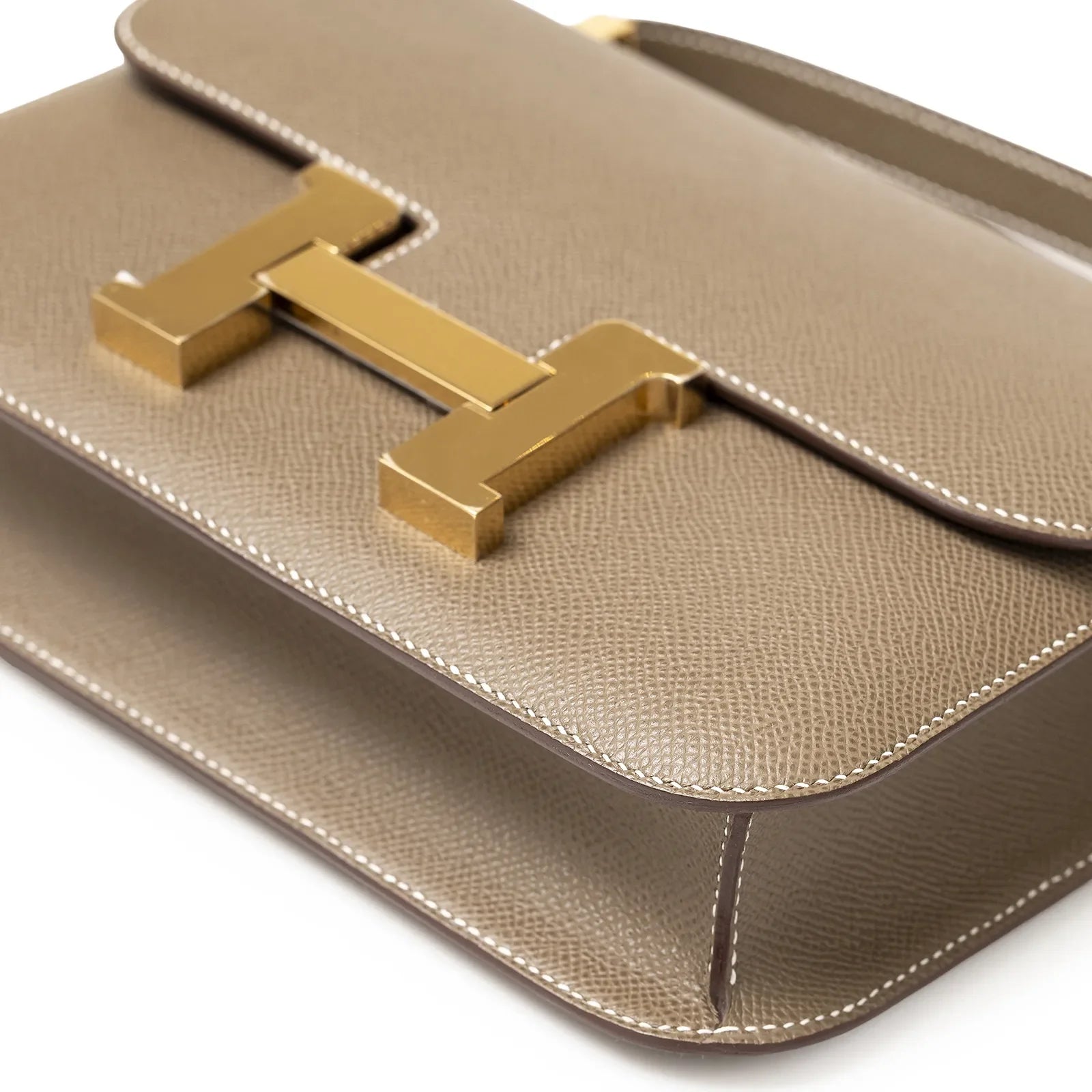 Angled close-up of Hermès Constance 24 Etoupe Epsom Gold Hardware showing textured leather and gold clasp detail