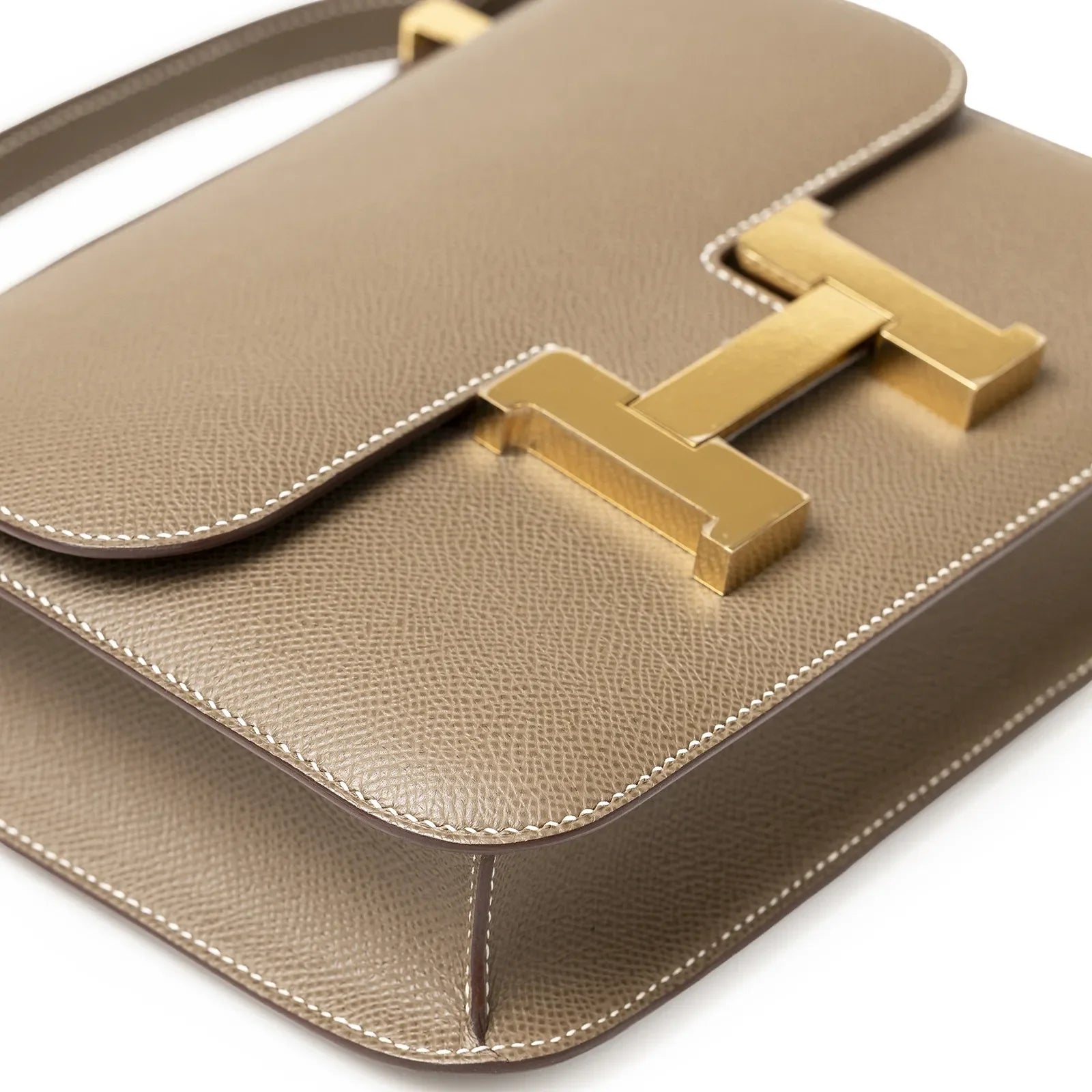 Close-up angled view of Hermès Constance 24 Etoupe Epsom Gold Hardware showing textured leather and gold clasp detail