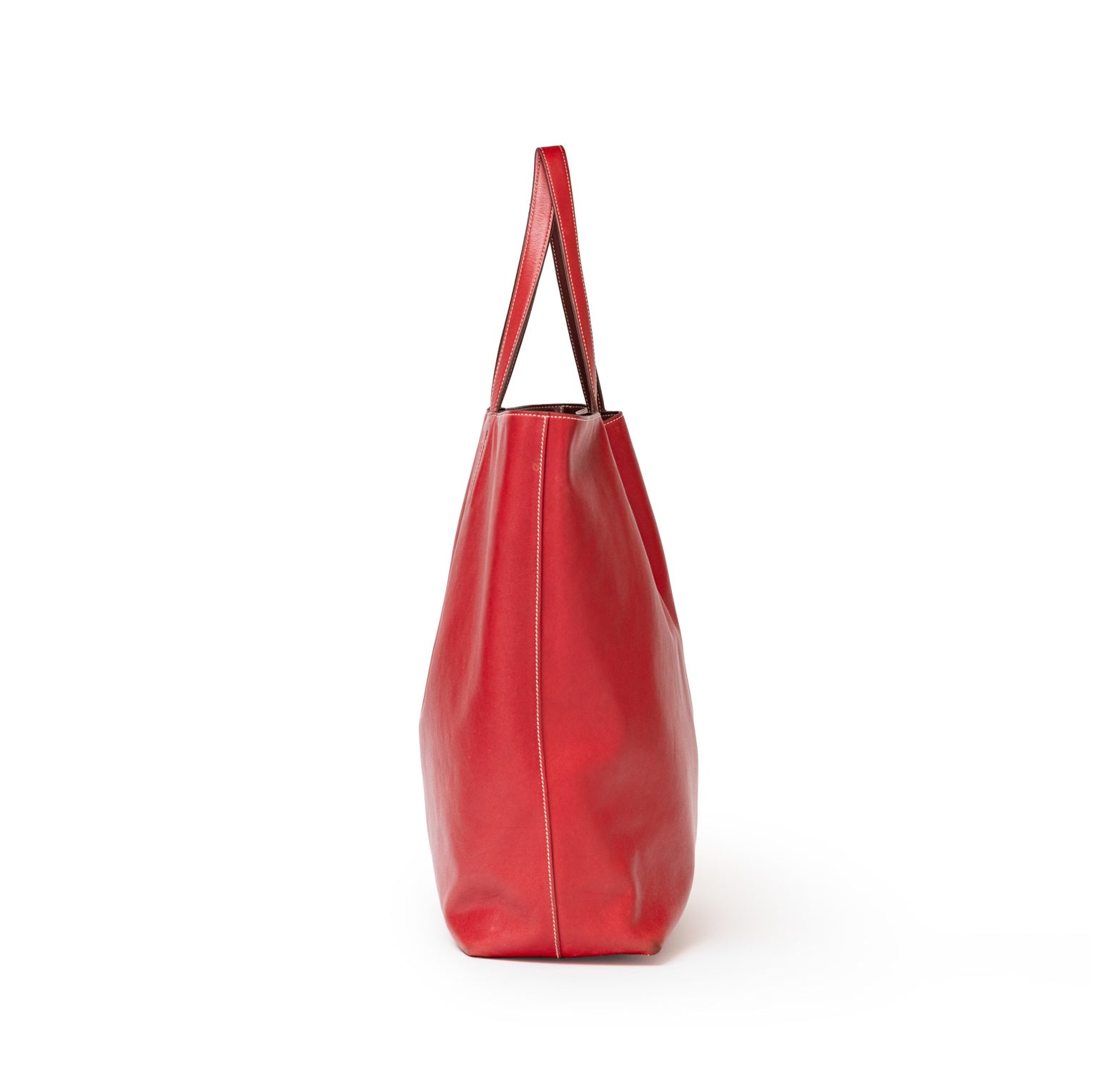 Side view of Hermès Double Sens 45 Rouge/Bicolor Swift tote highlighting its sleek red leather silhouette and strap detail