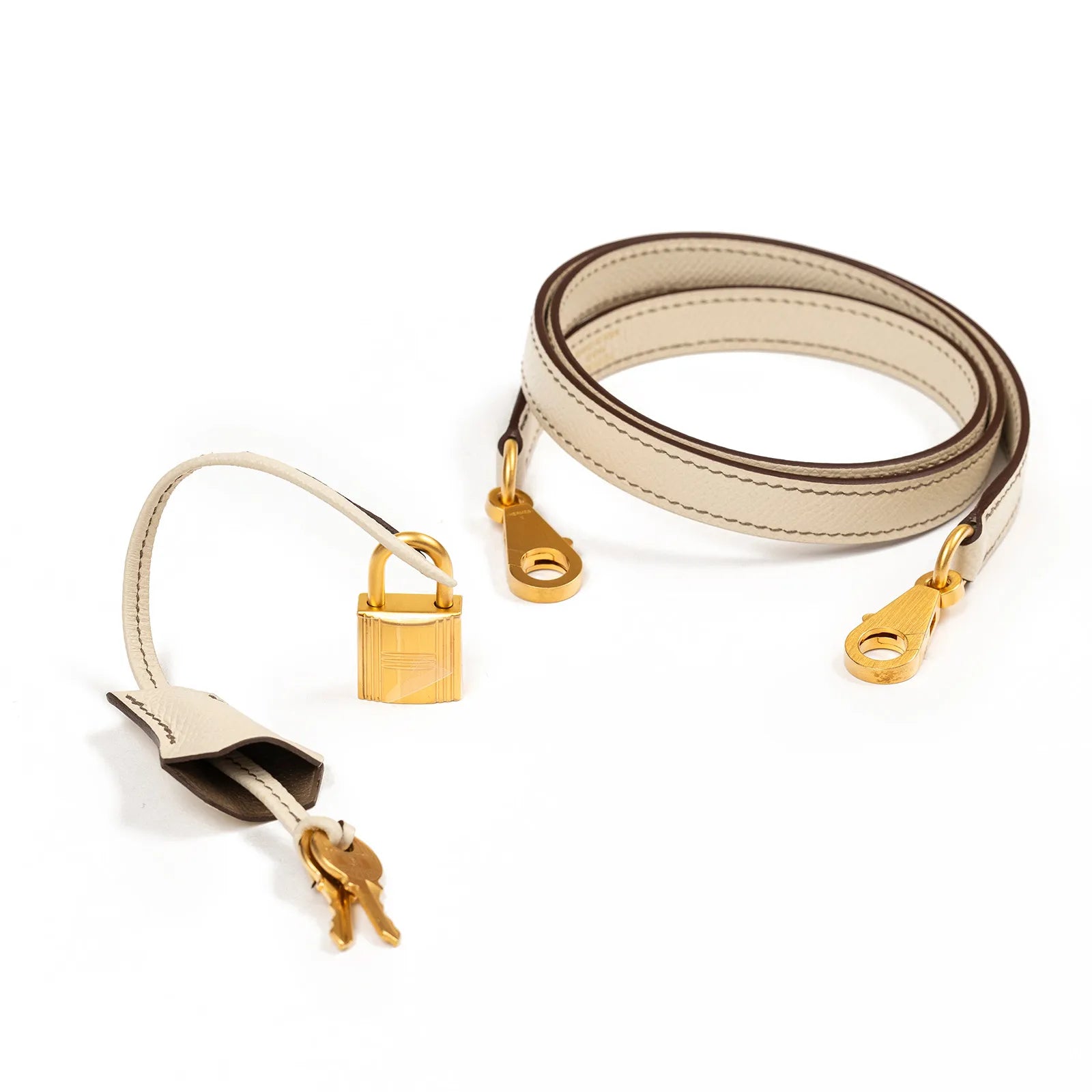 Close-up of Hermès Horseshoe Kelly 25 Sellier Etoupe/Craie Epsom leather strap with brushed gold hardware and keys accessory