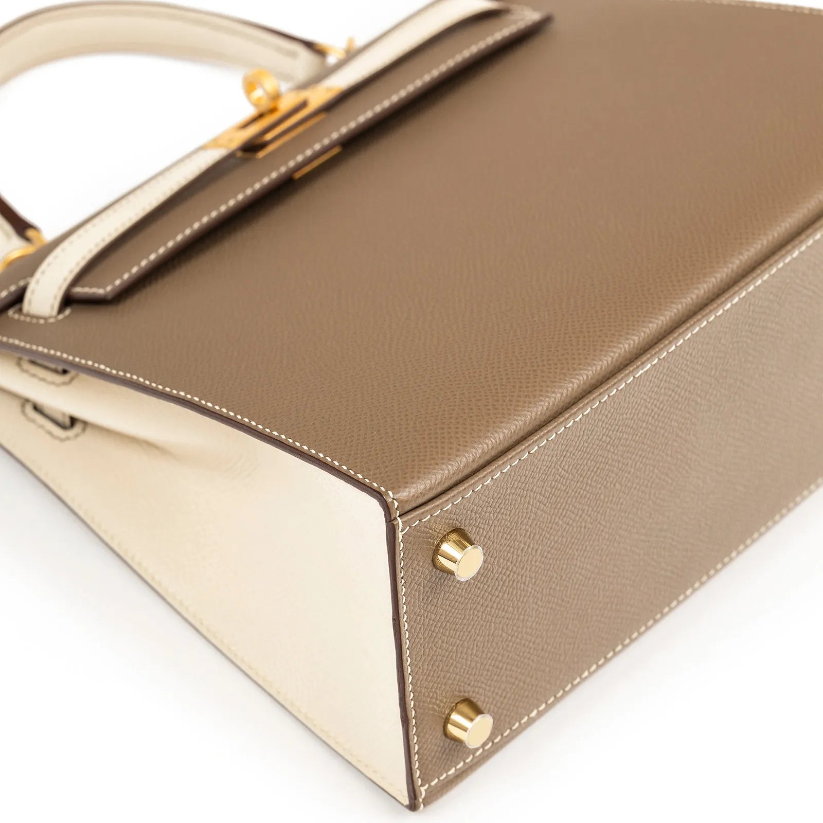 Close-up angled shot of Hermès Horseshoe Kelly 25 Sellier Etoupe/Craie Epsom Brushed Gold Hardware base and stitching detail