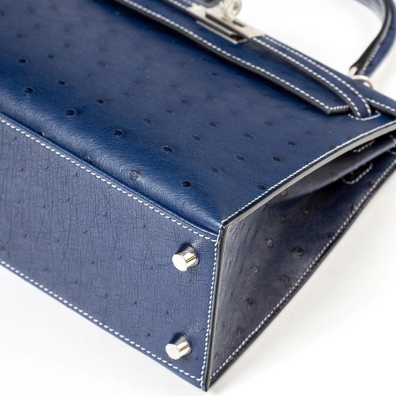 Close-up angled shot of corner and hardware on Hermès Horseshoe Kelly 25 Sellier Ostrich Blue Iris/Gris Brushed Palladium Hardware
