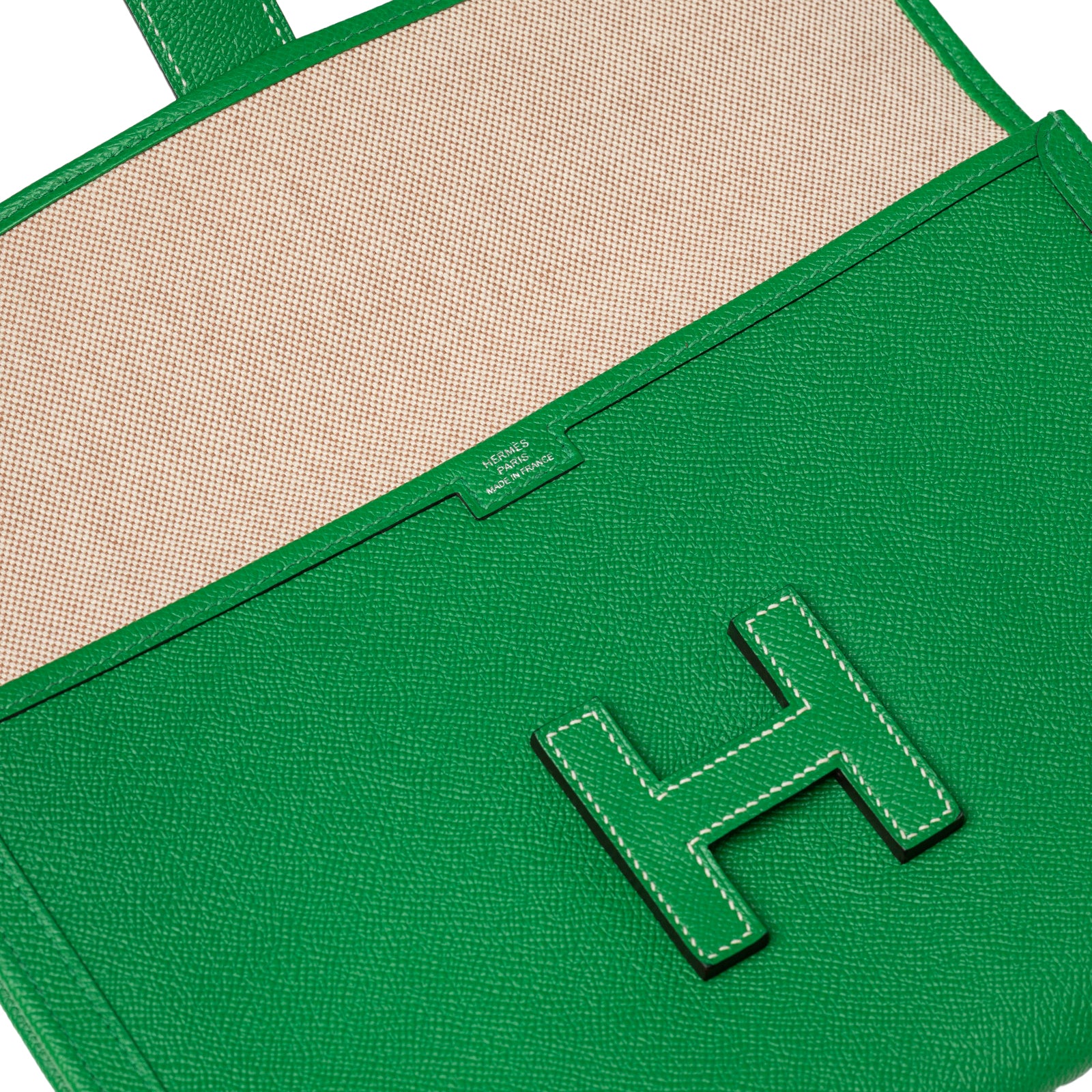 Close-up of Hermès Jige PM Bamboo Green Epsom showing interior fabric and leather exterior with H clasp detail