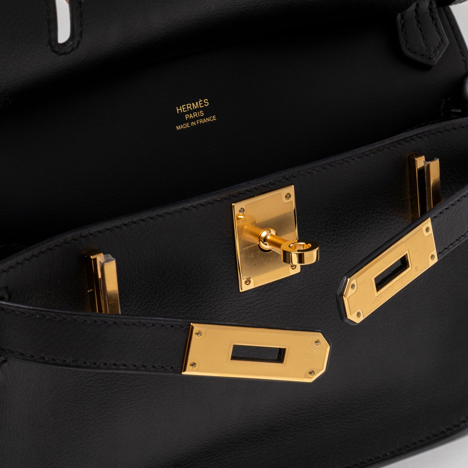 Close-up of gold hardware lock and key detail inside Hermès Jypsiere Mini Black Evergrain Gold Hardware handbag